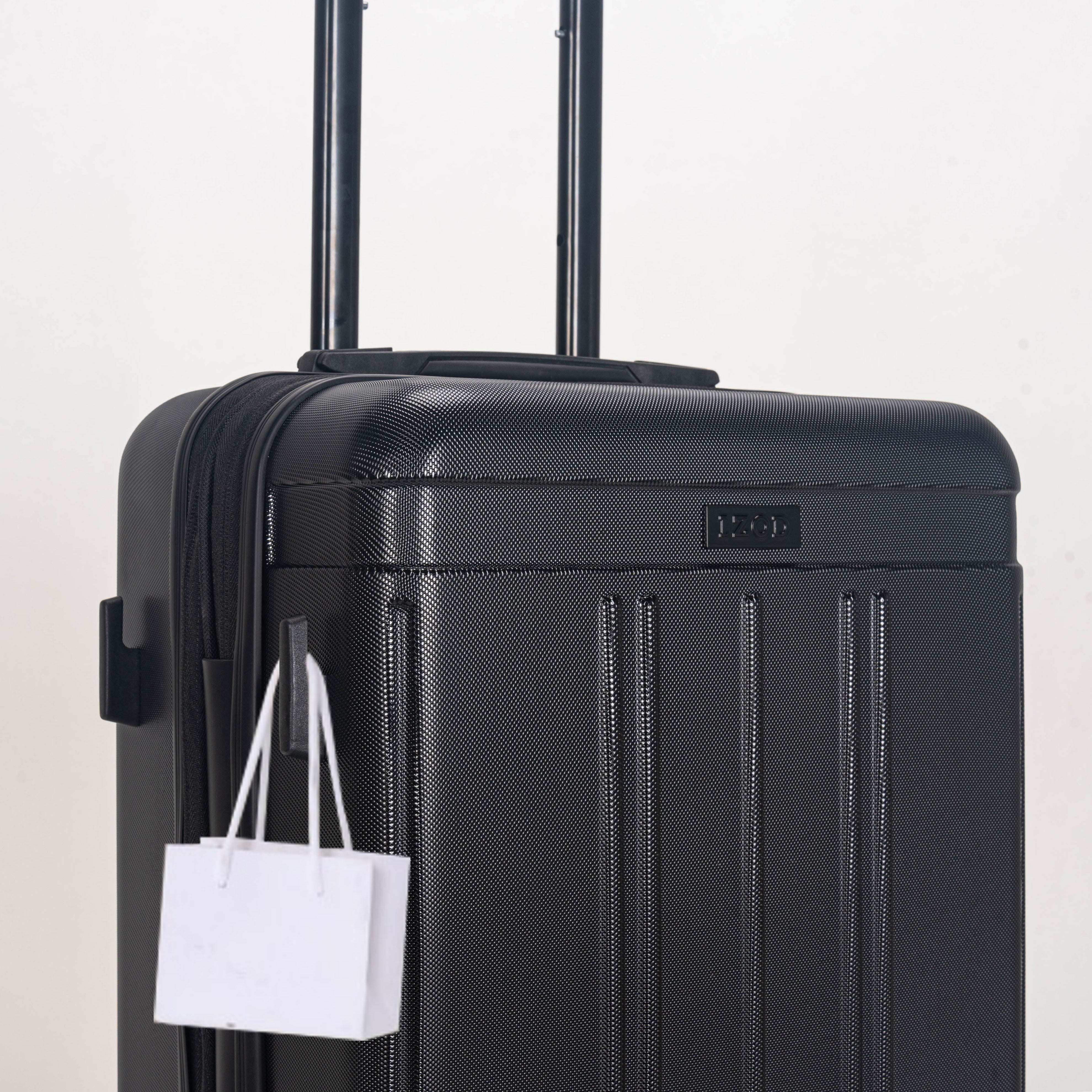 Black suitcase with a white shopping bag attached on a light gray background