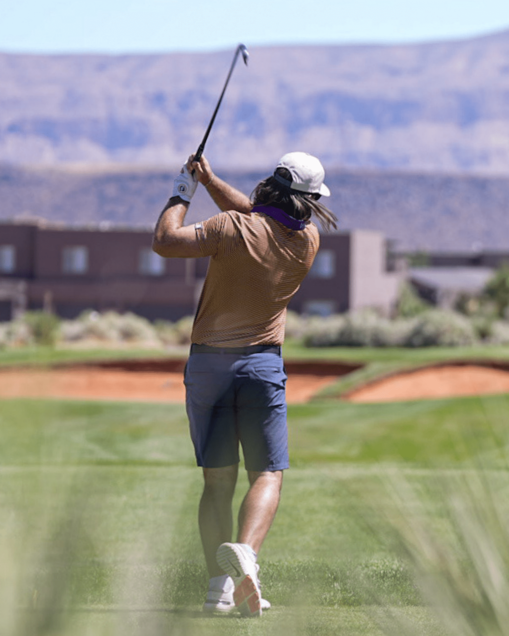 Person playing golf on a course with mountains in the background