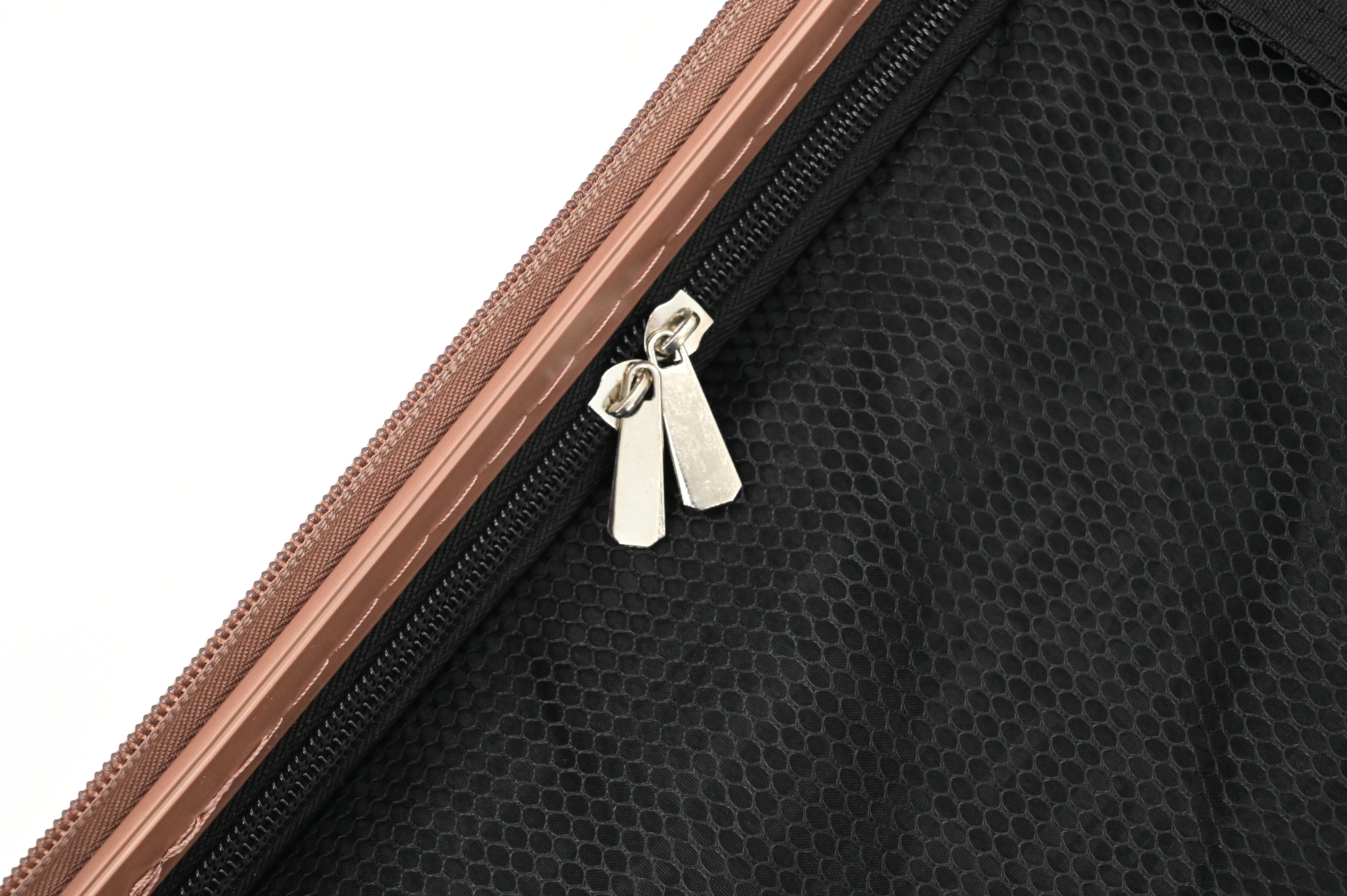 Close-up of a black textured bag with a brown zipper and silver tag on a white background