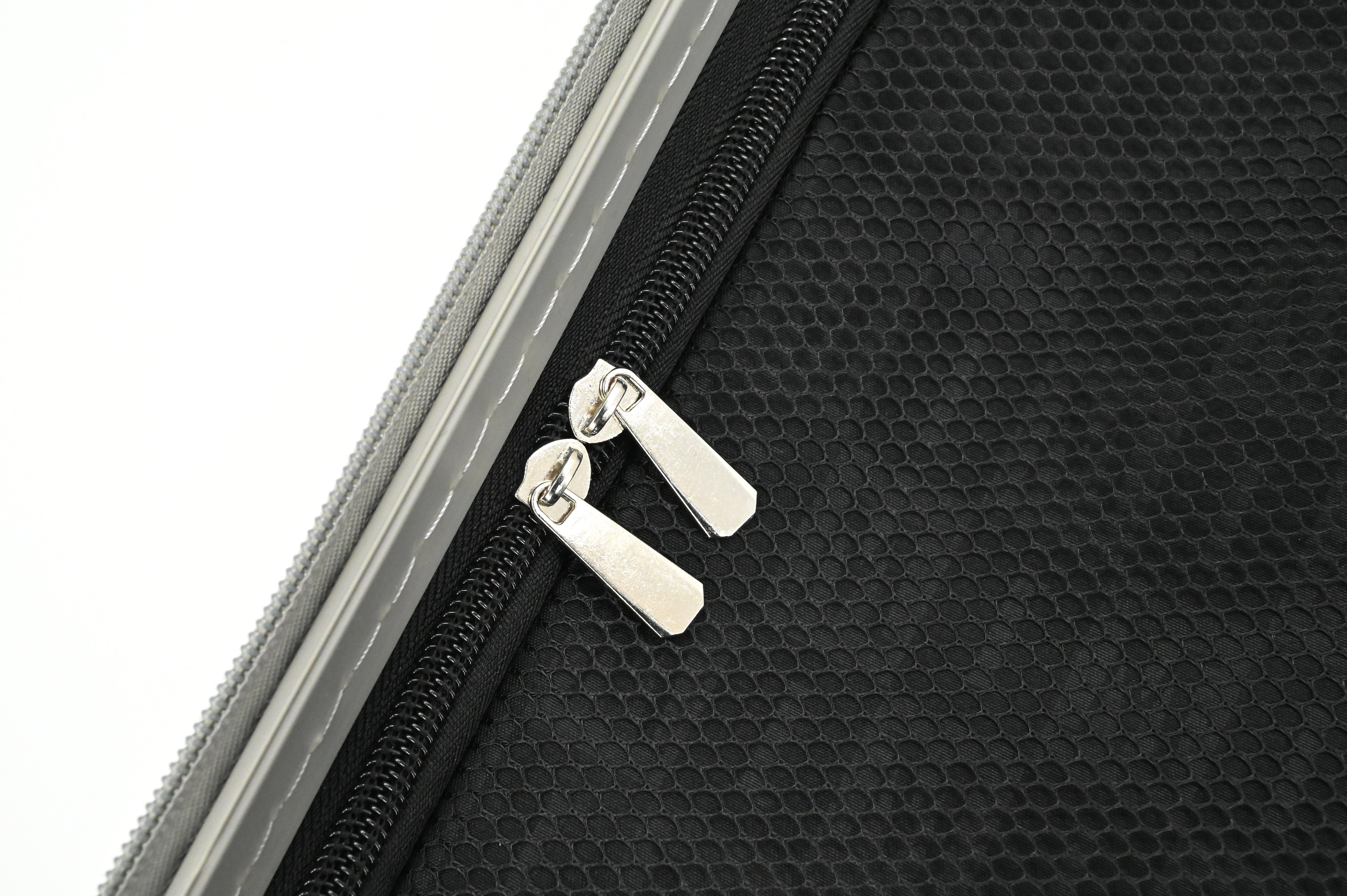 Close-up of a black textured bag with a silver zipper on a white background