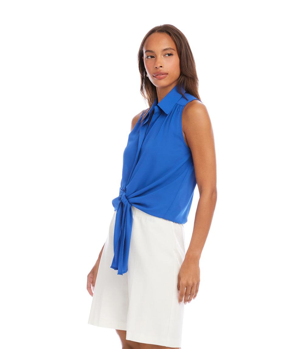 Woman wearing a blue sleeveless top with a tie detail and white skirt on a white background