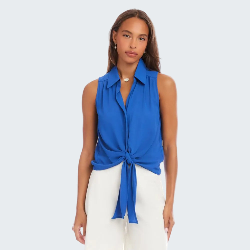 Woman wearing a blue sleeveless top with a knot detail and white shorts on a white background