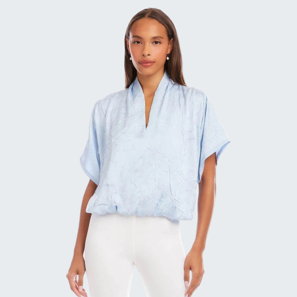 Woman wearing a light blue kimono-style top on a white background