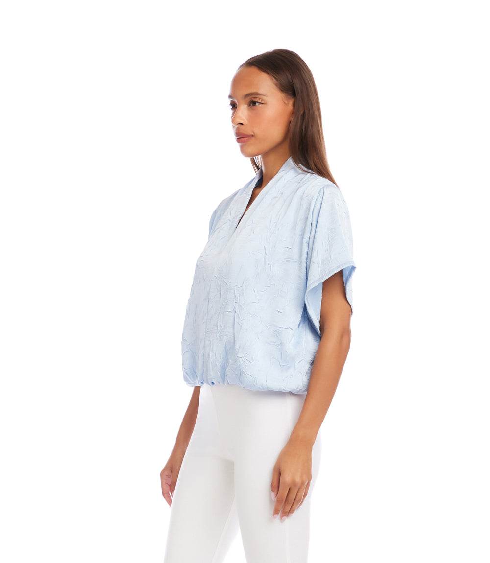Woman wearing a light blue striped shirt and white pants on a white background