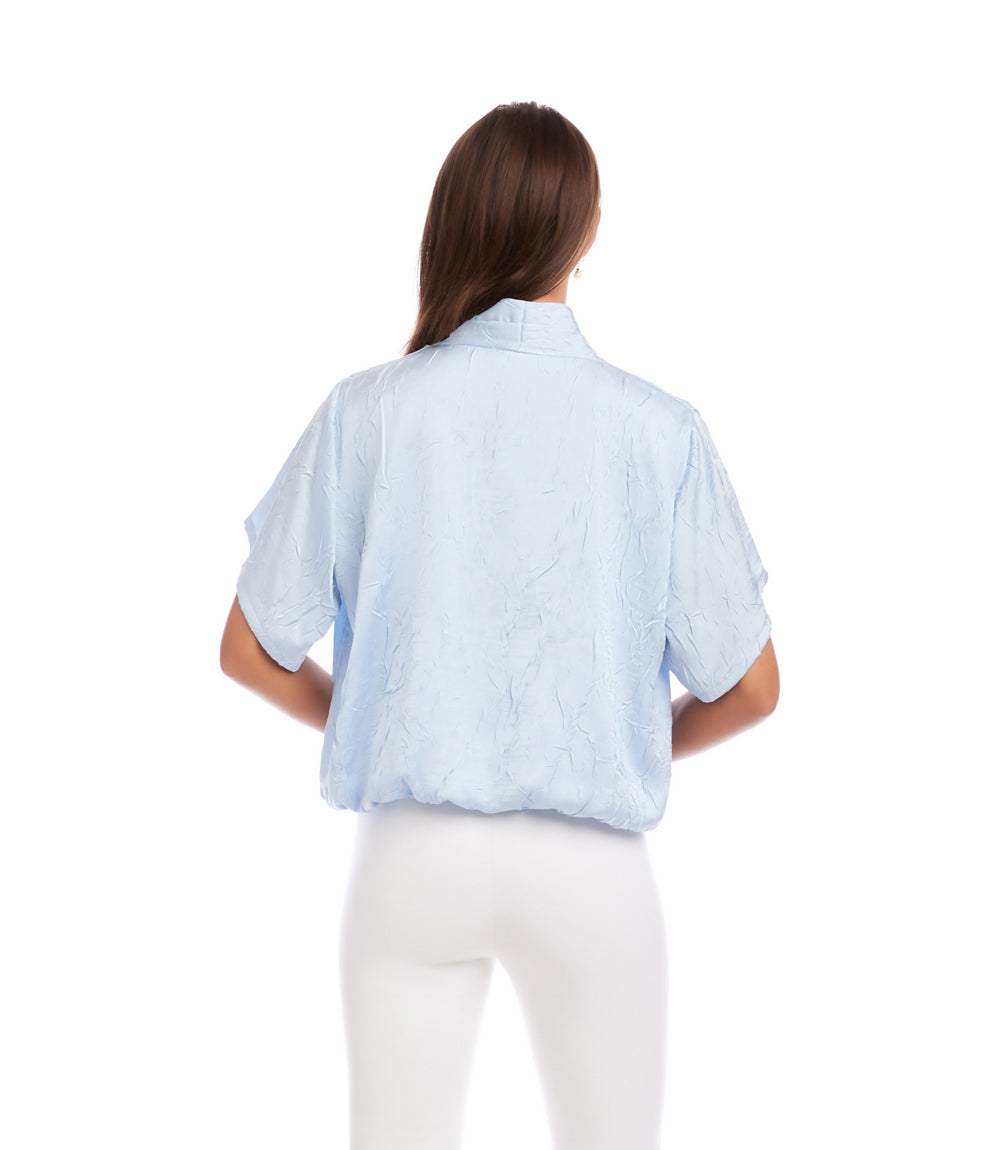 Woman wearing a light blue shirt and white pants on a white background