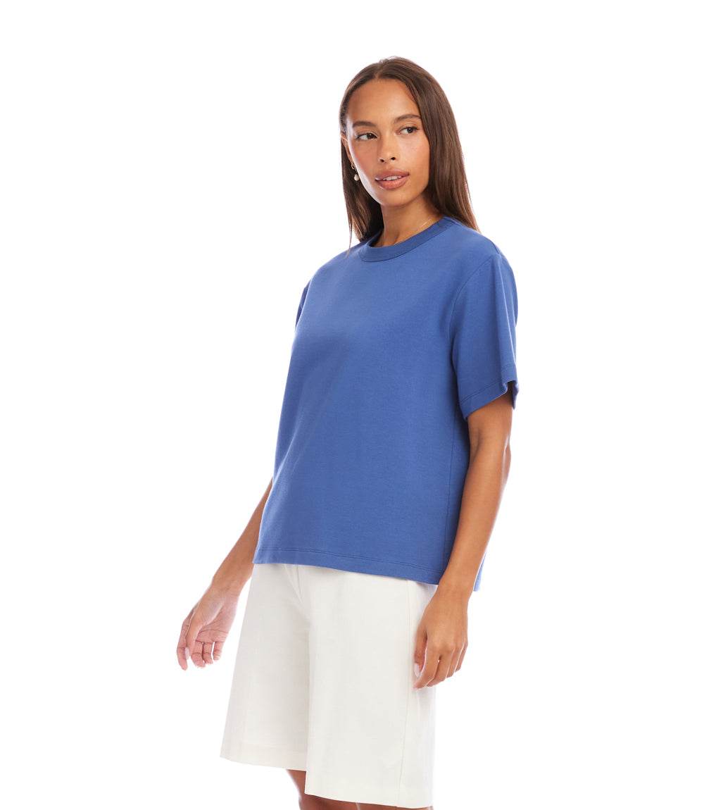 Woman wearing a blue top and white shorts on a white background