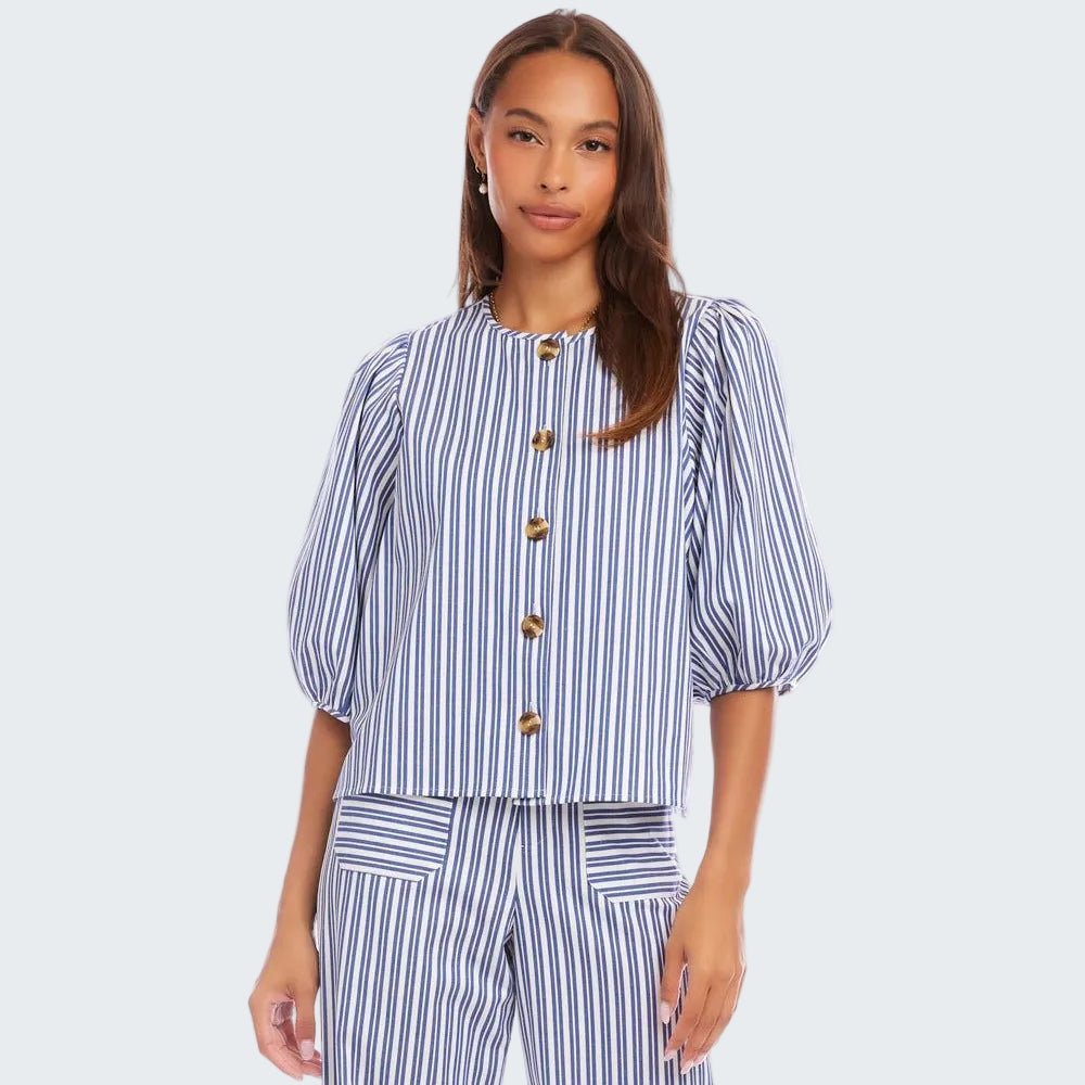 Woman wearing a blue and white striped outfit with gold buttons on a white background