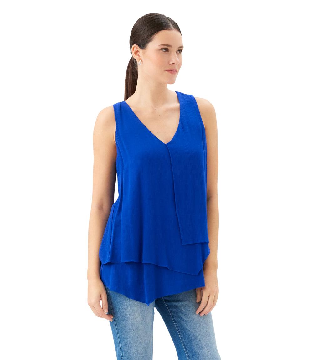 Woman wearing a blue sleeveless top and jeans on a white background