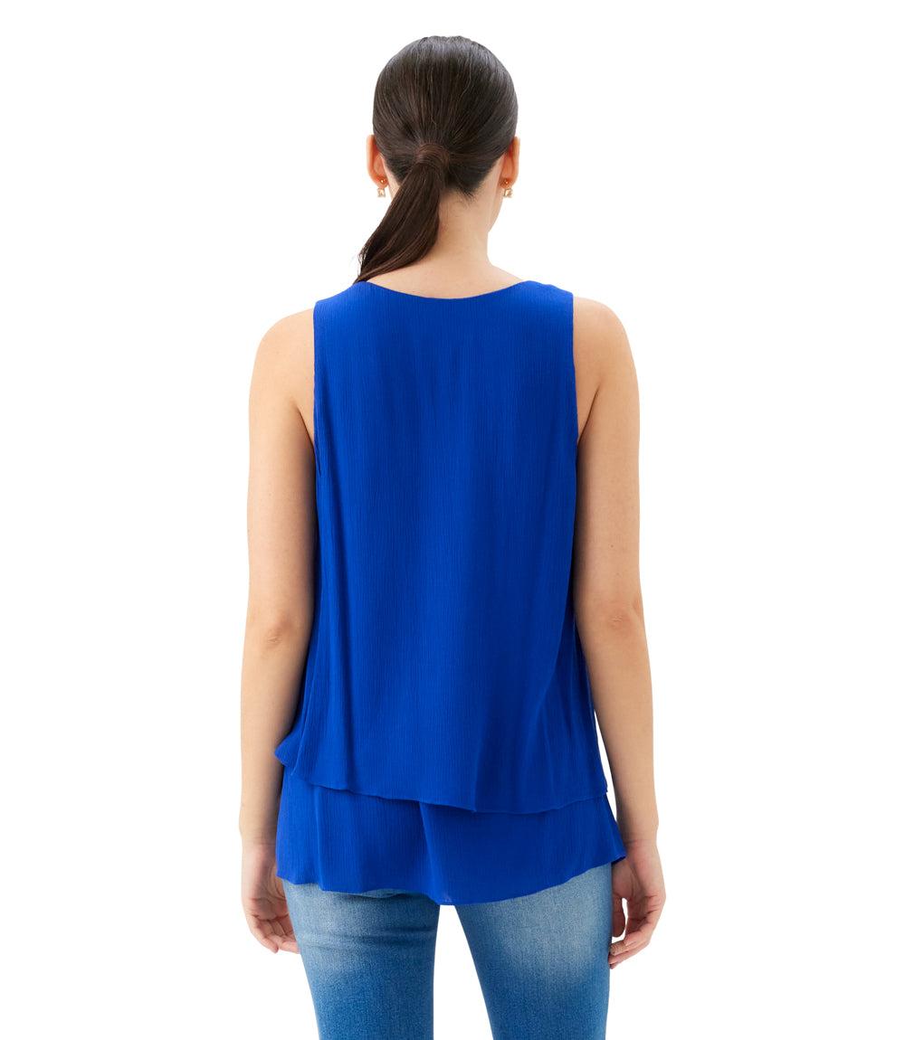 Woman wearing a blue sleeveless top and jeans on a white background