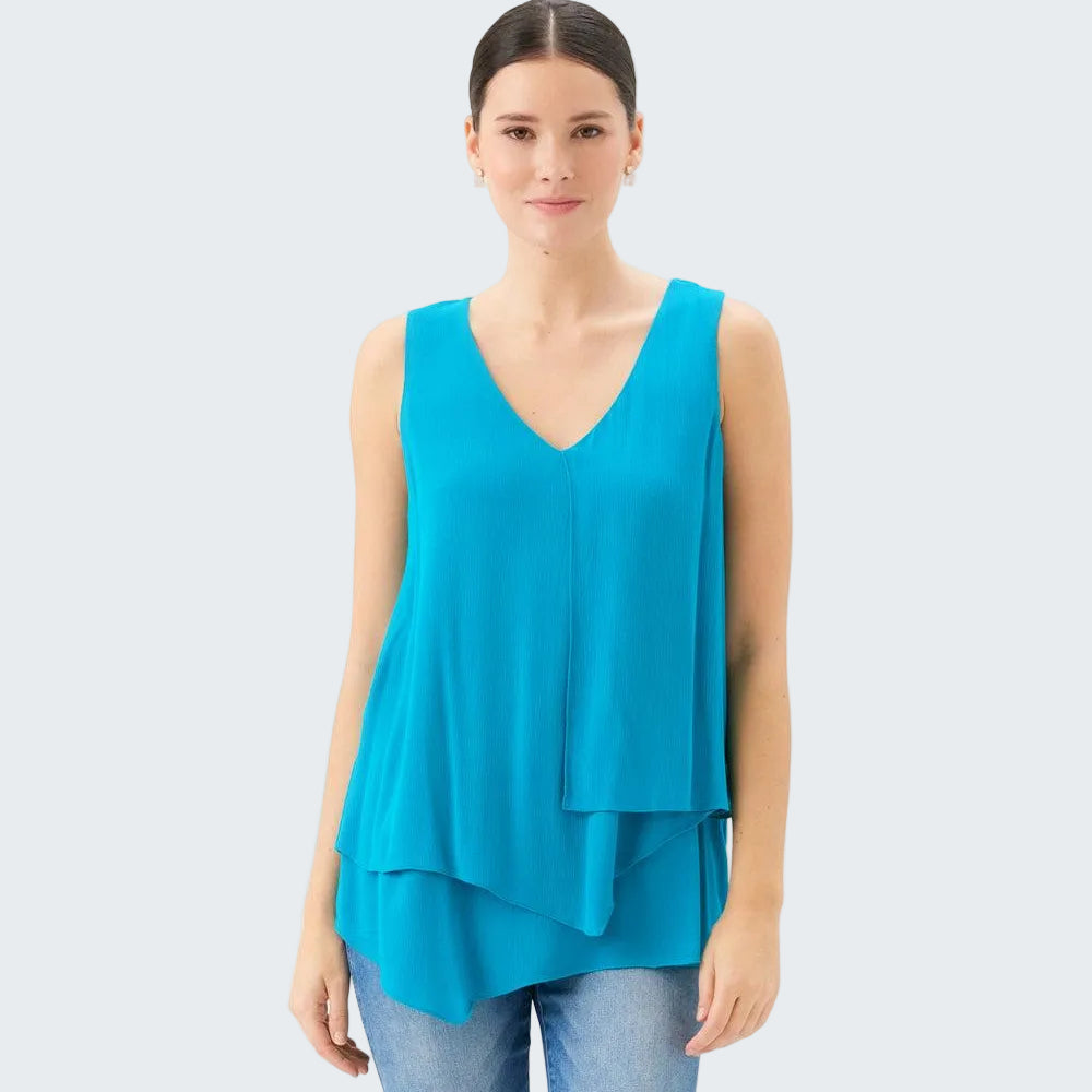 Woman wearing a turquoise sleeveless top and jeans on a white background