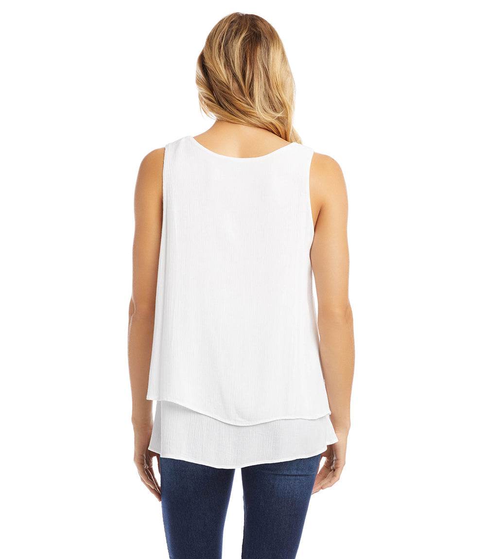 Woman wearing a white layered top and blue jeans on a white background