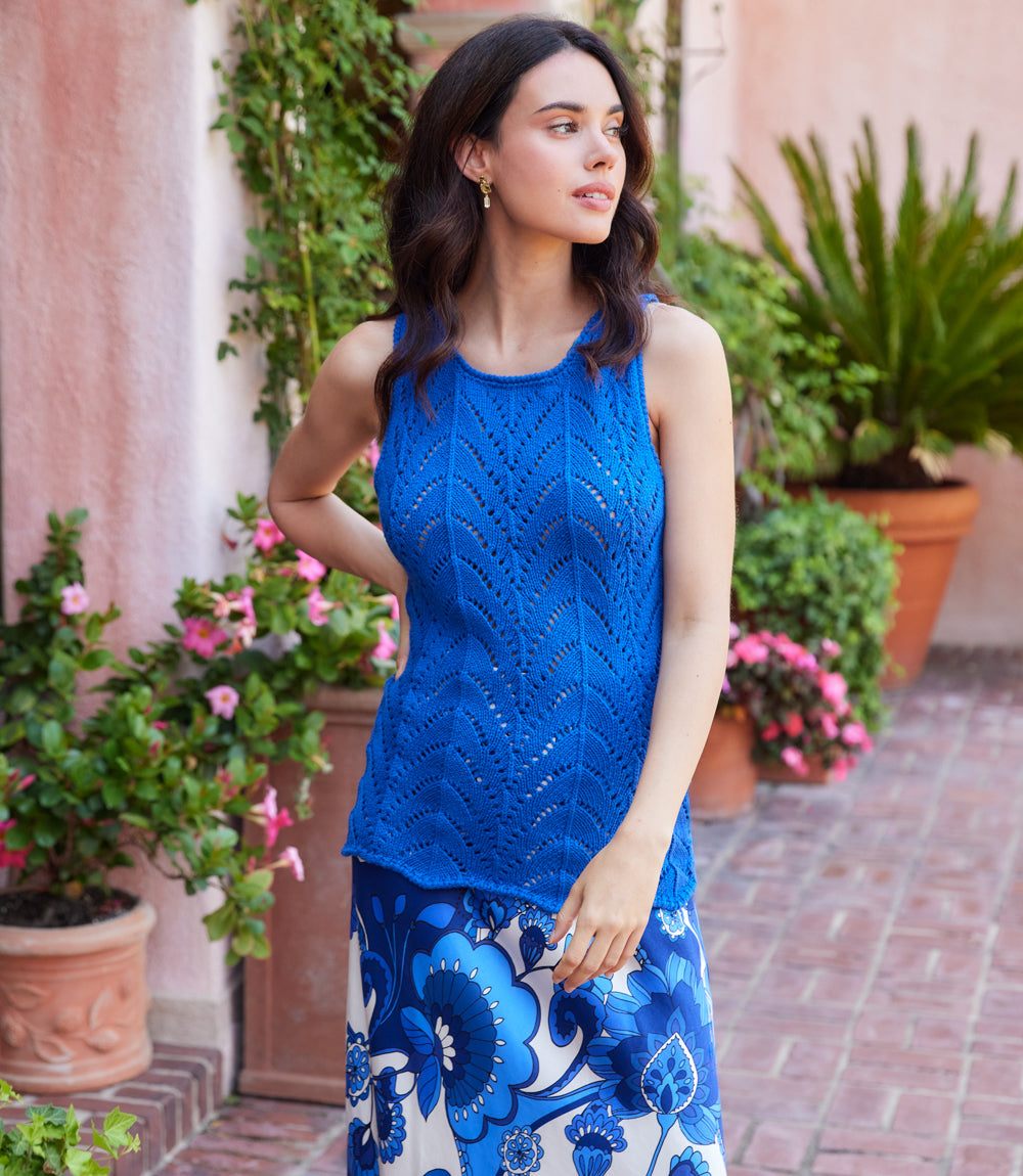 Woman wearing a blue sleeveless top with a floral patterned skirt in an outdoor setting.