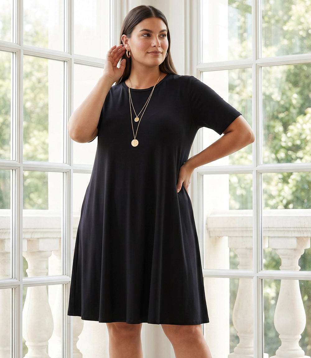 Woman wearing a black dress standing in front of a large window with white frames.