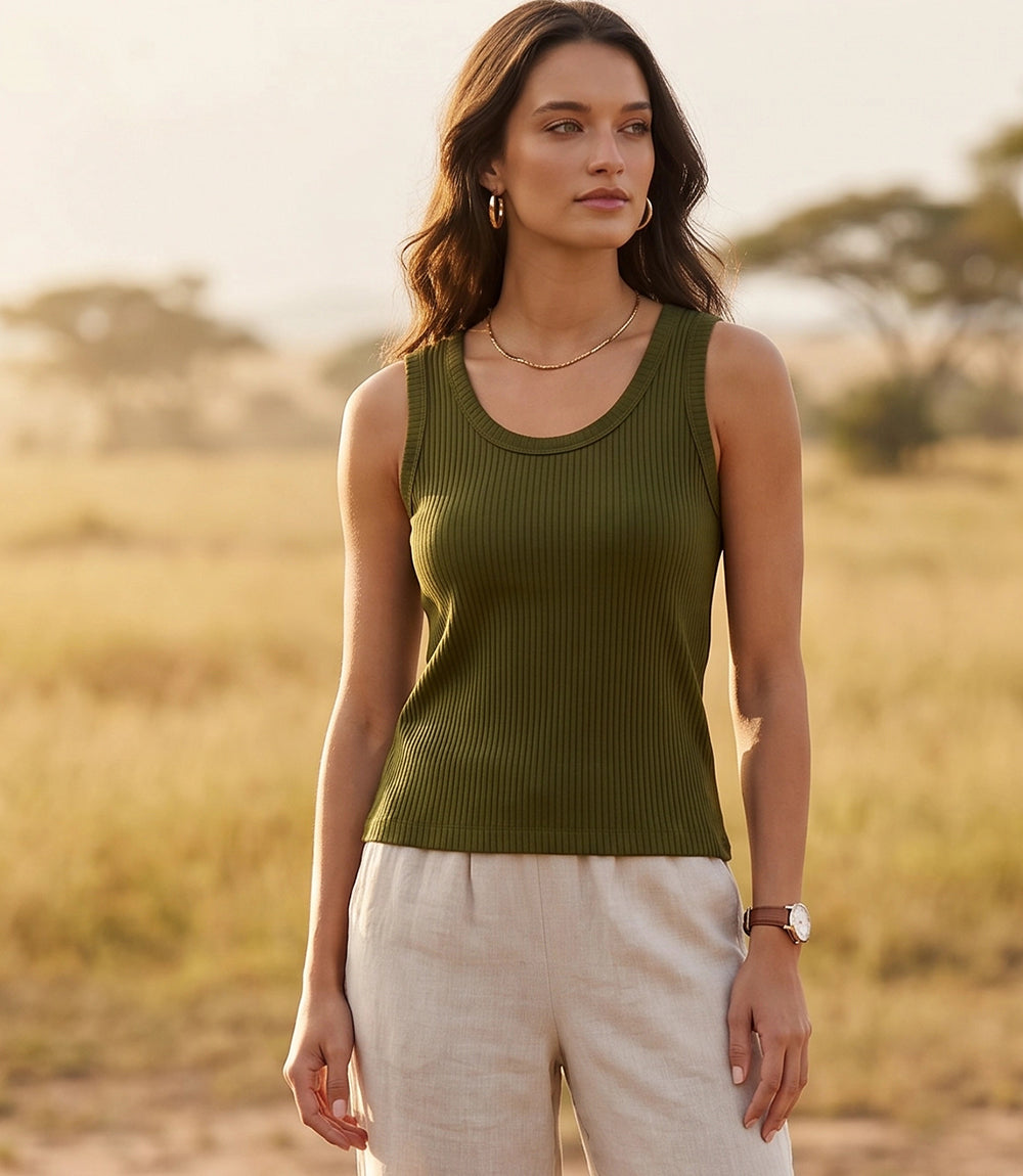 Woman wearing a green tank top and beige pants in a natural setting
