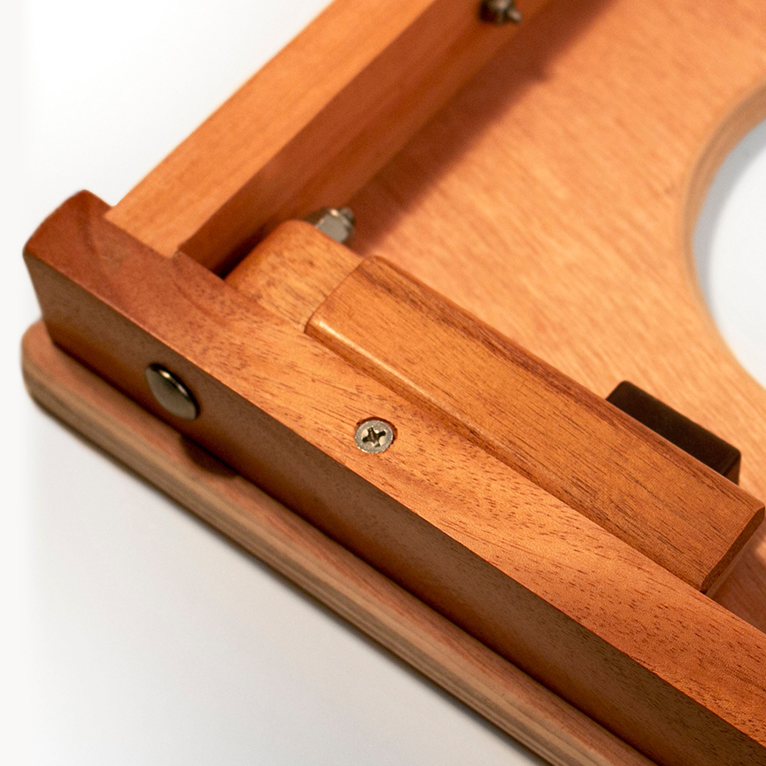 Close-up of a wooden product showing warm medium-brown wood grain, a screw fastener, and a white background.
