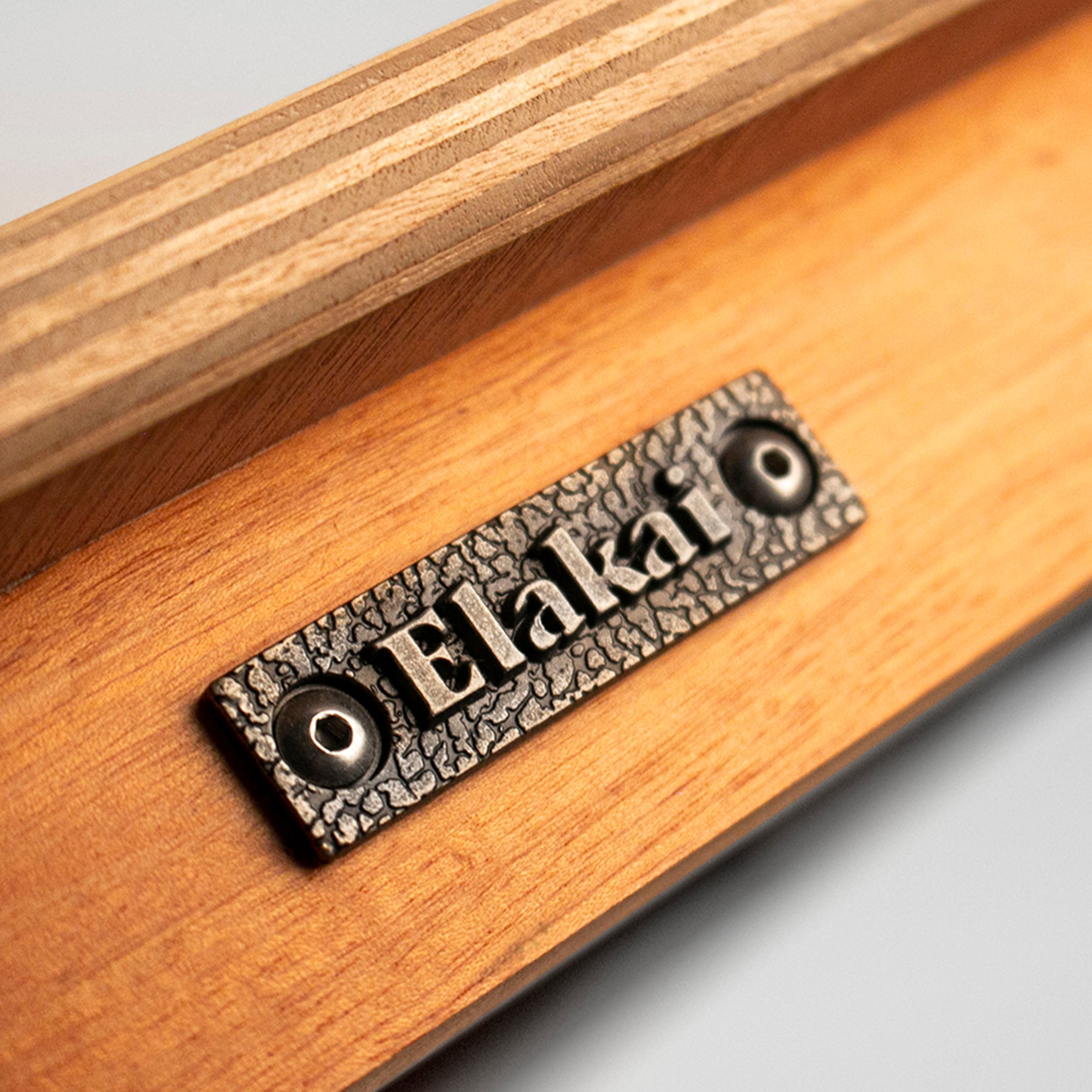 Wooden surface with a metal plaque displaying the brand 'Elakat'.