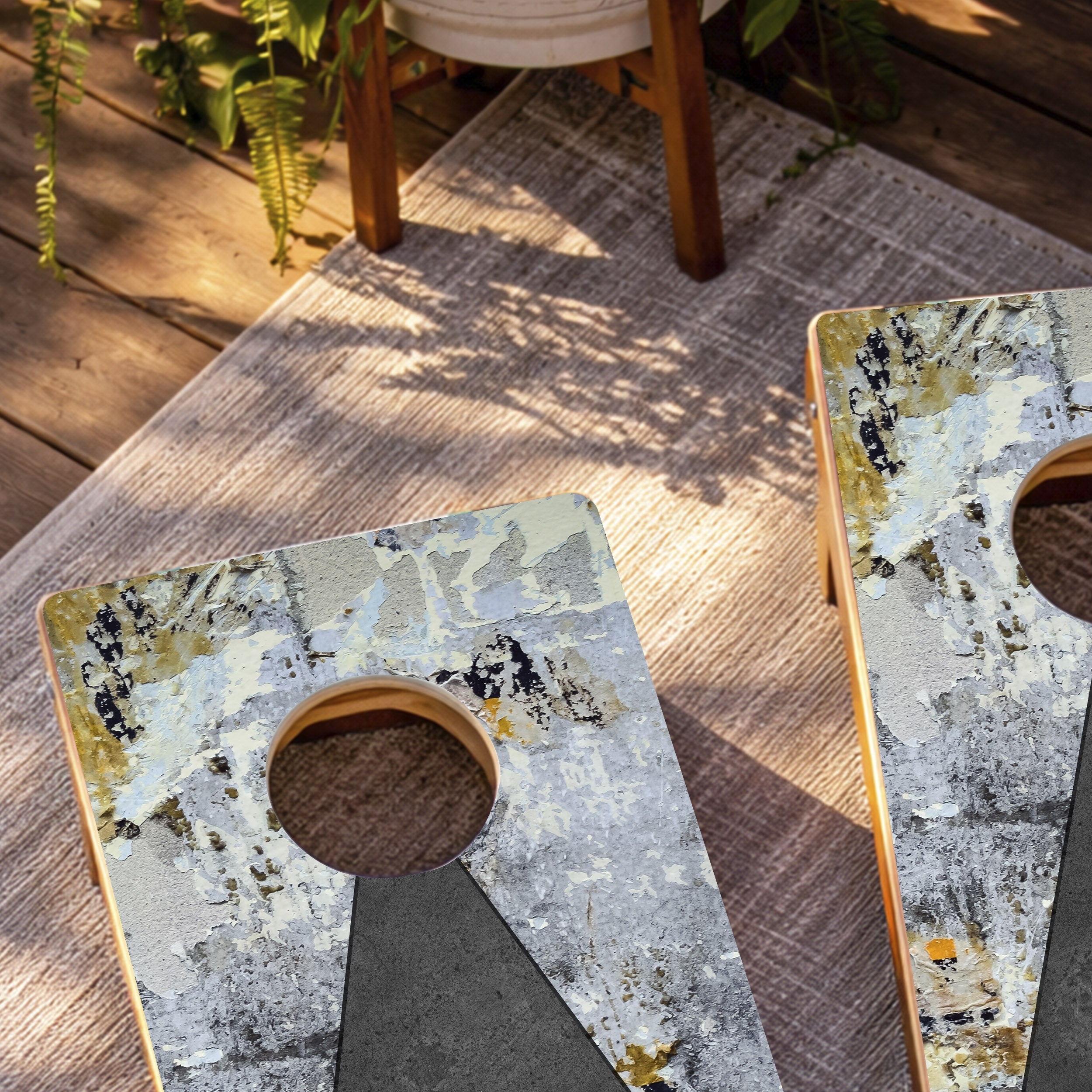 Two decorative stone coasters on a wooden surface with plants in the background