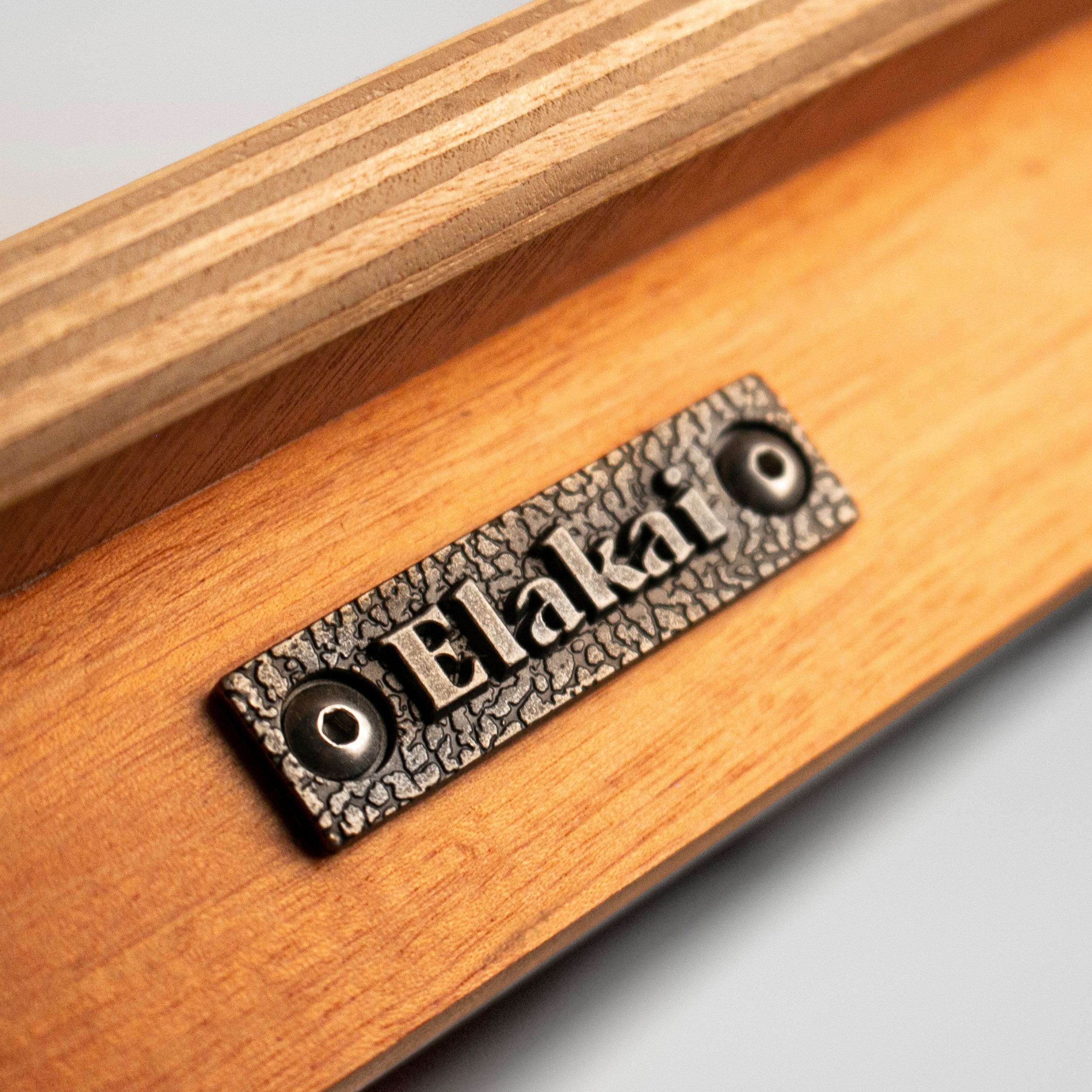 Wooden surface with a metal plaque displaying the brand 'Elakal'.