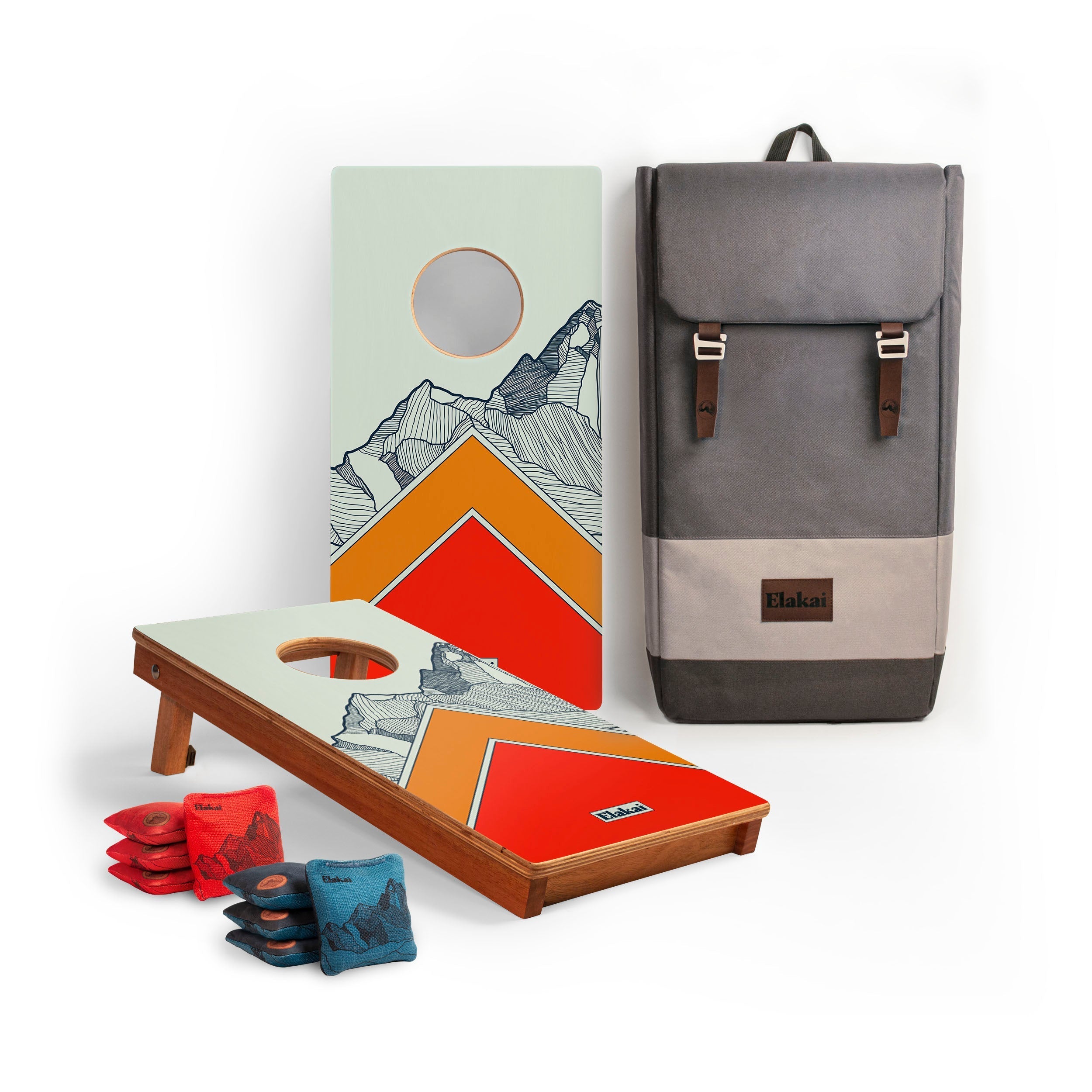 Cornhole board with mountain design, cornhole bags, and a gray backpack on a white background