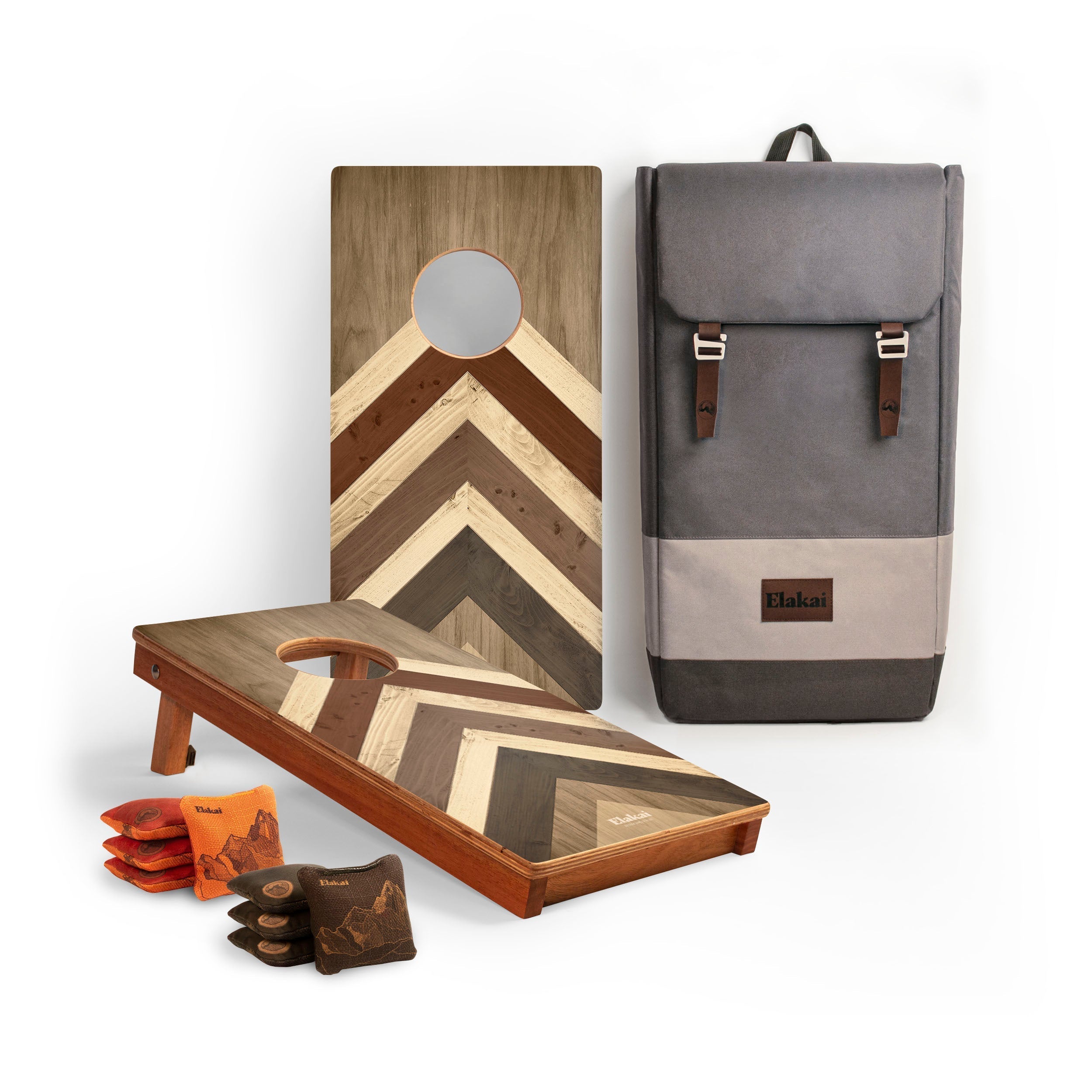 Cornhole boards with a geometric design, a gray backpack, and bags on a white background