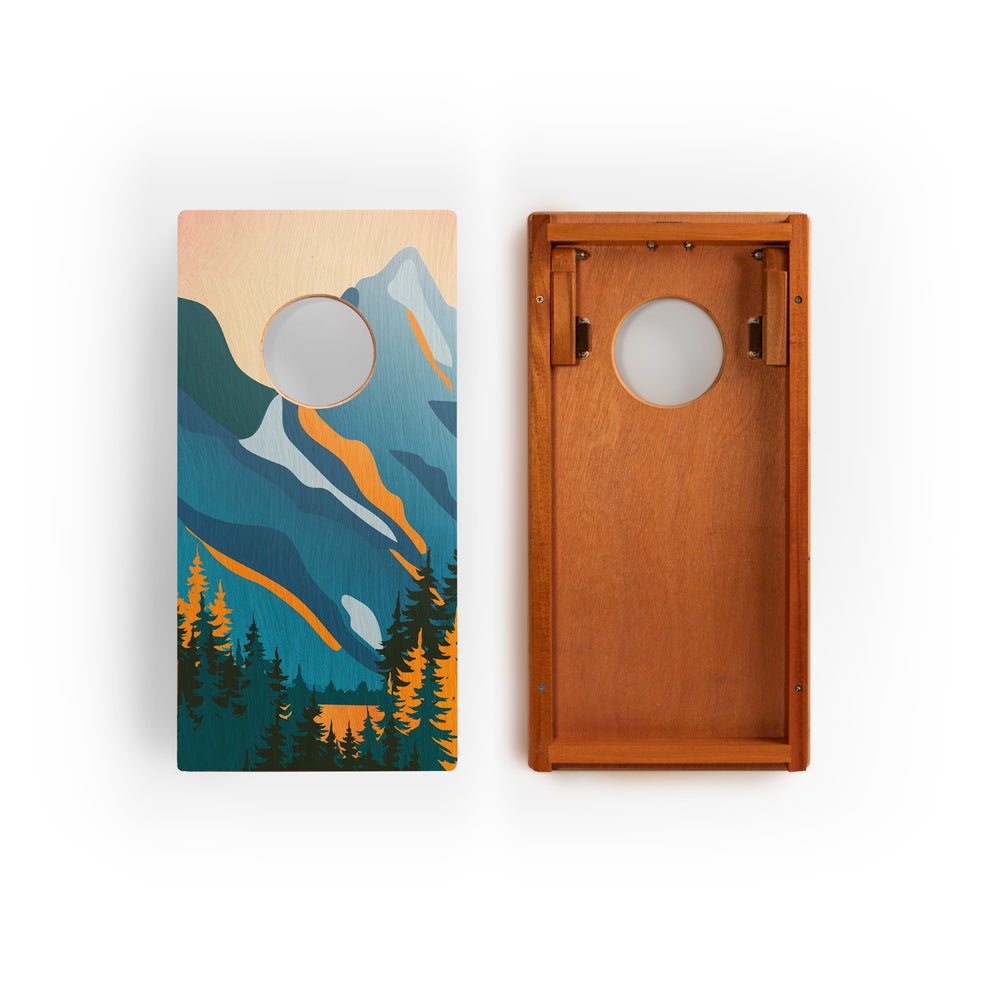 Two cornhole boards with mountain and forest design on a white background