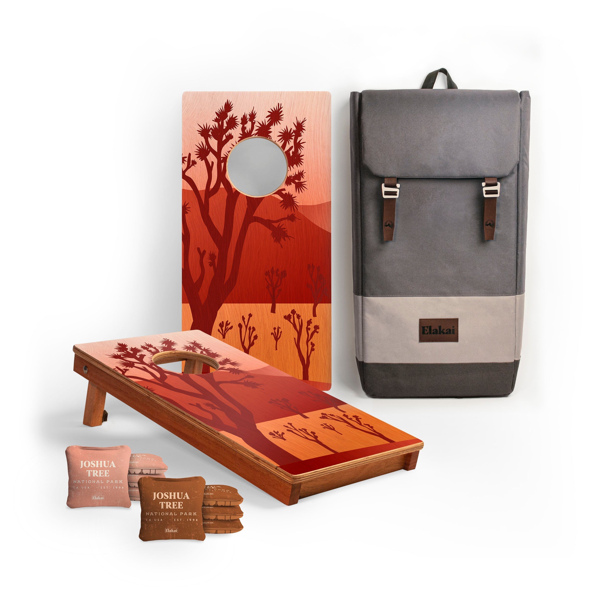 Cornhole board with tree design, cornhole bags, and a backpack on a white background