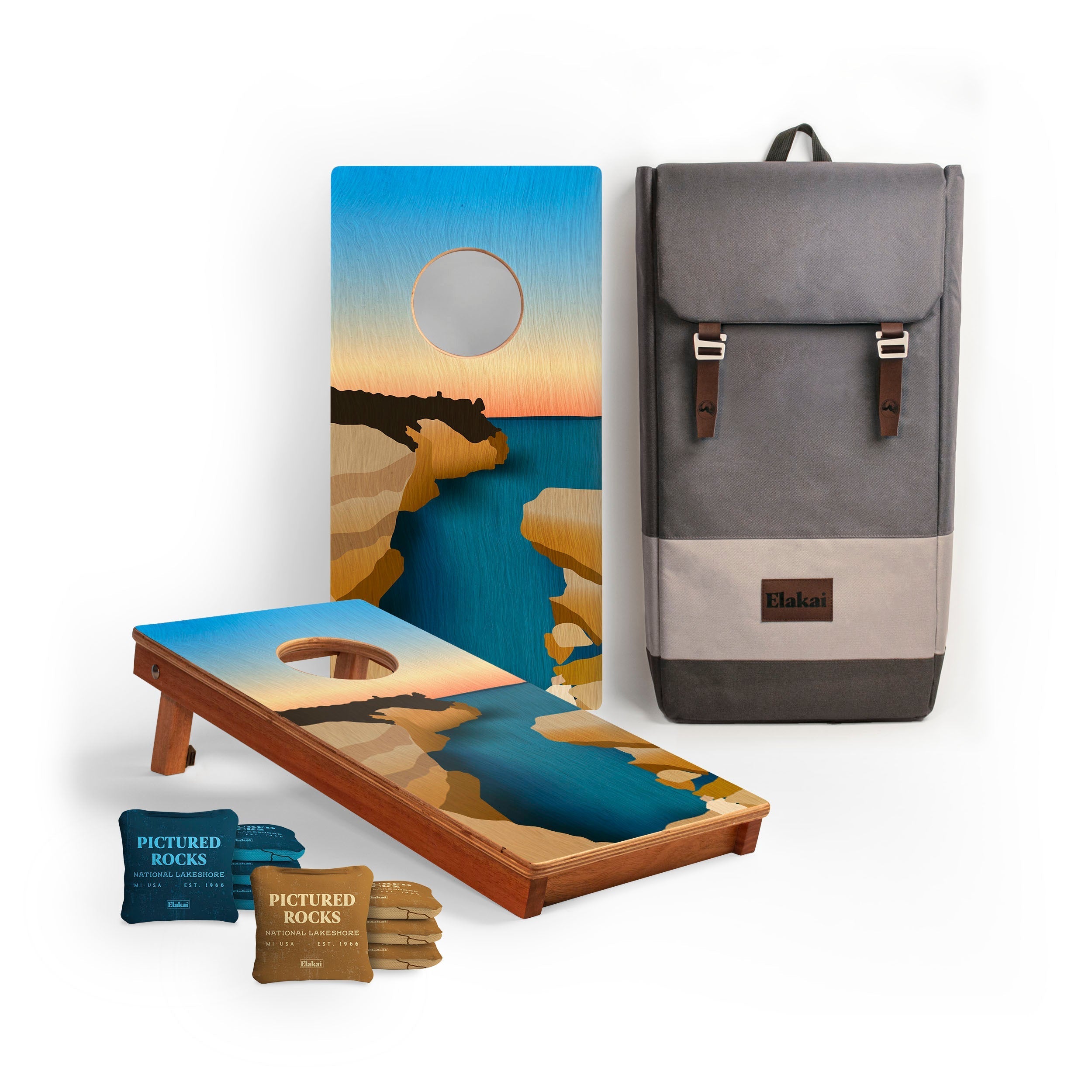 Cornhole boards with sunset design, backpack, and snacks on a white background