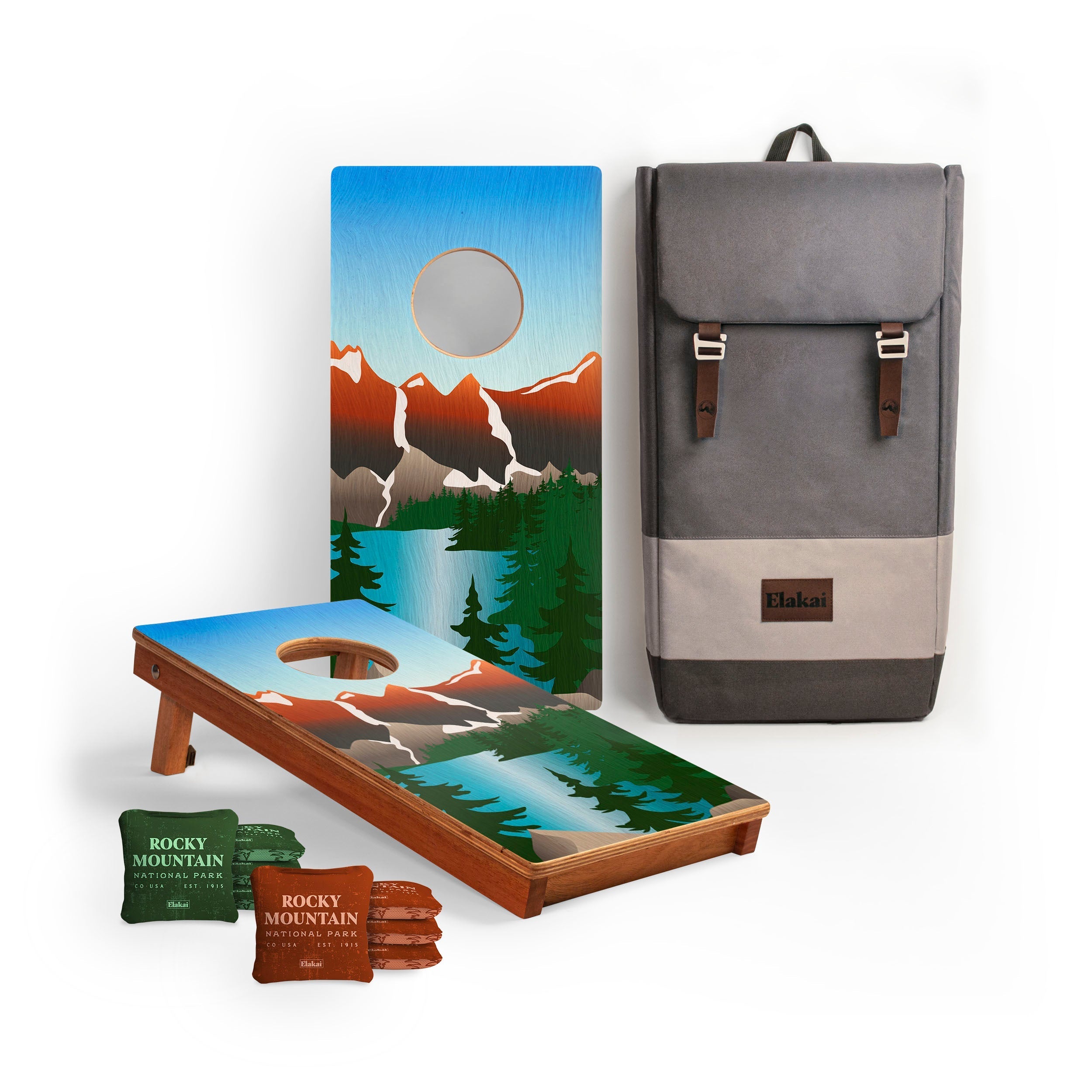 Cornhole boards with mountain design, cornhole bags, and a backpack on a white background