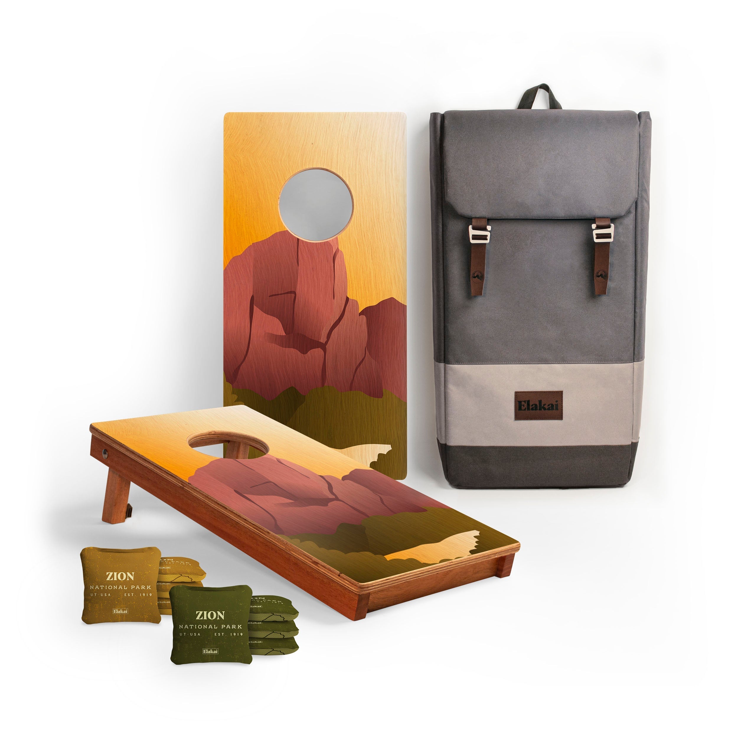 Cornhole boards with mountain design, cornhole bags, and a backpack on a white background