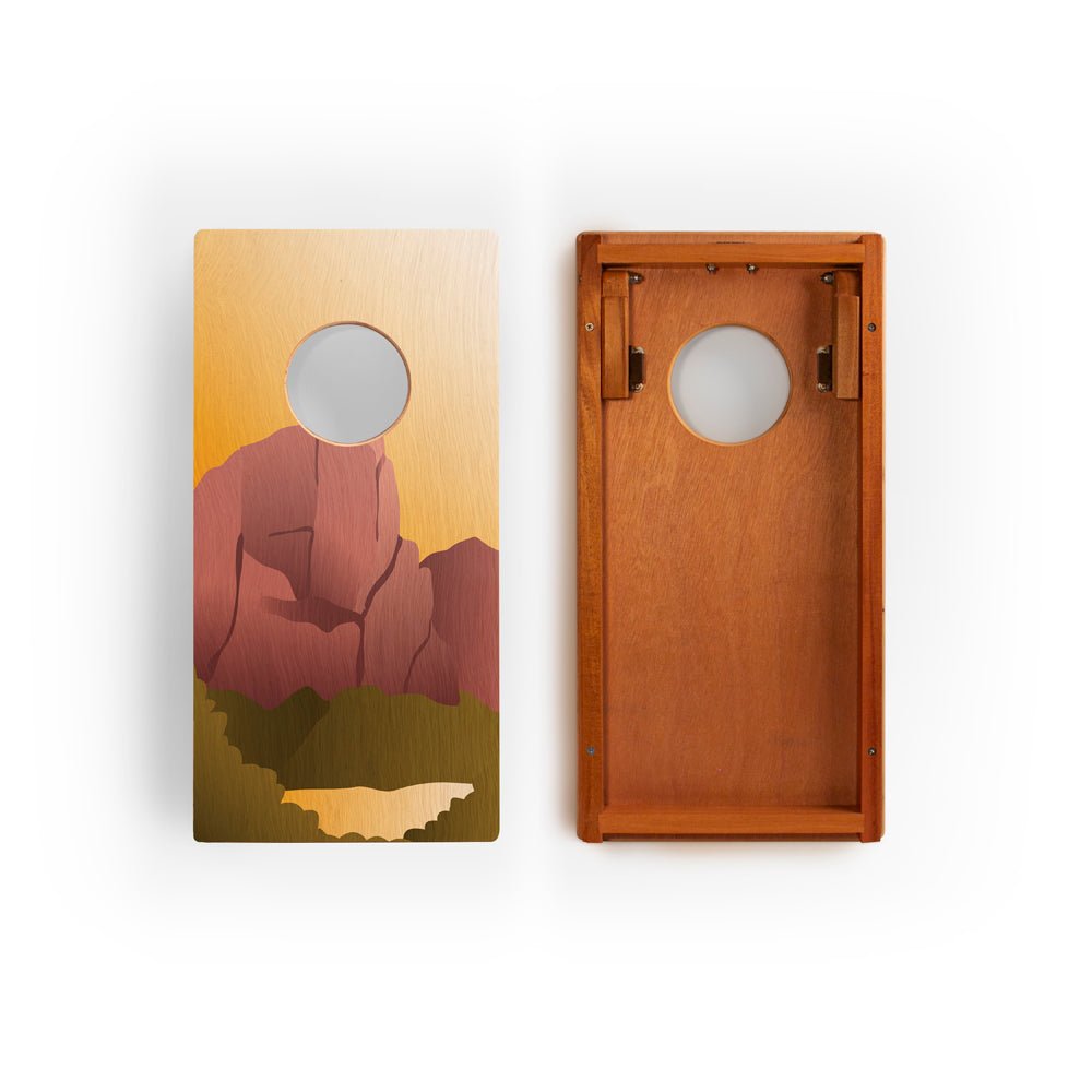 Two wooden cornhole boards with a mountain design on a white background