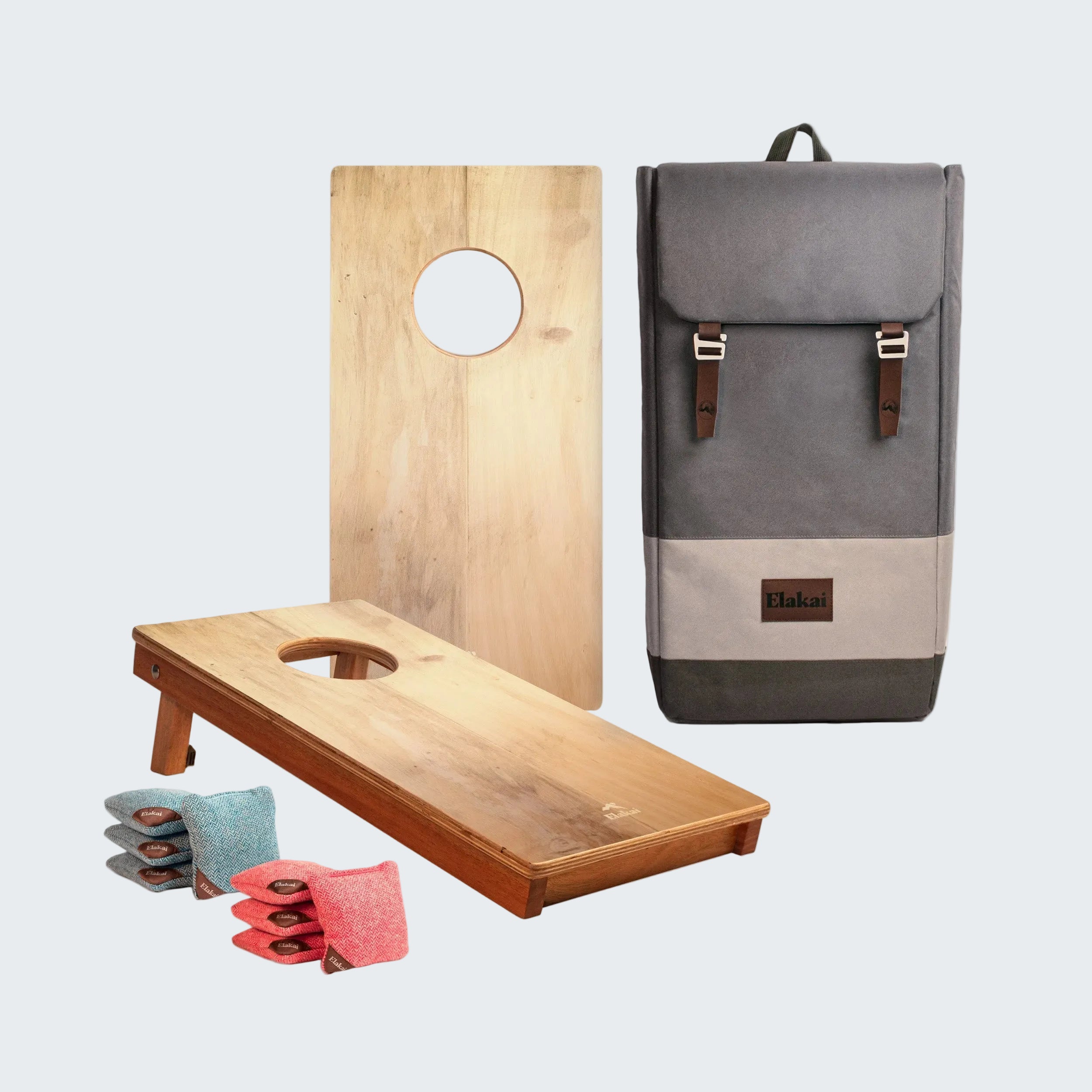 Two wooden cornhole boards with bags and a gray backpack on a white background