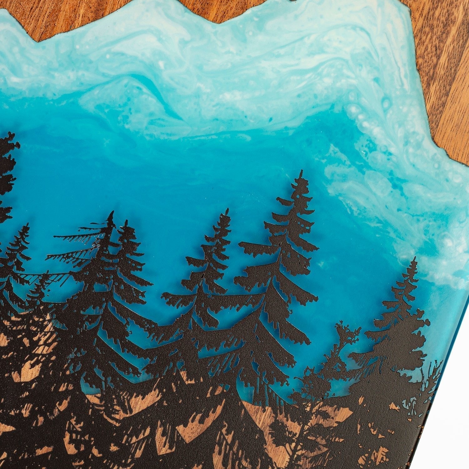 Decorative tray with blue resin design and black tree silhouettes on a wooden surface