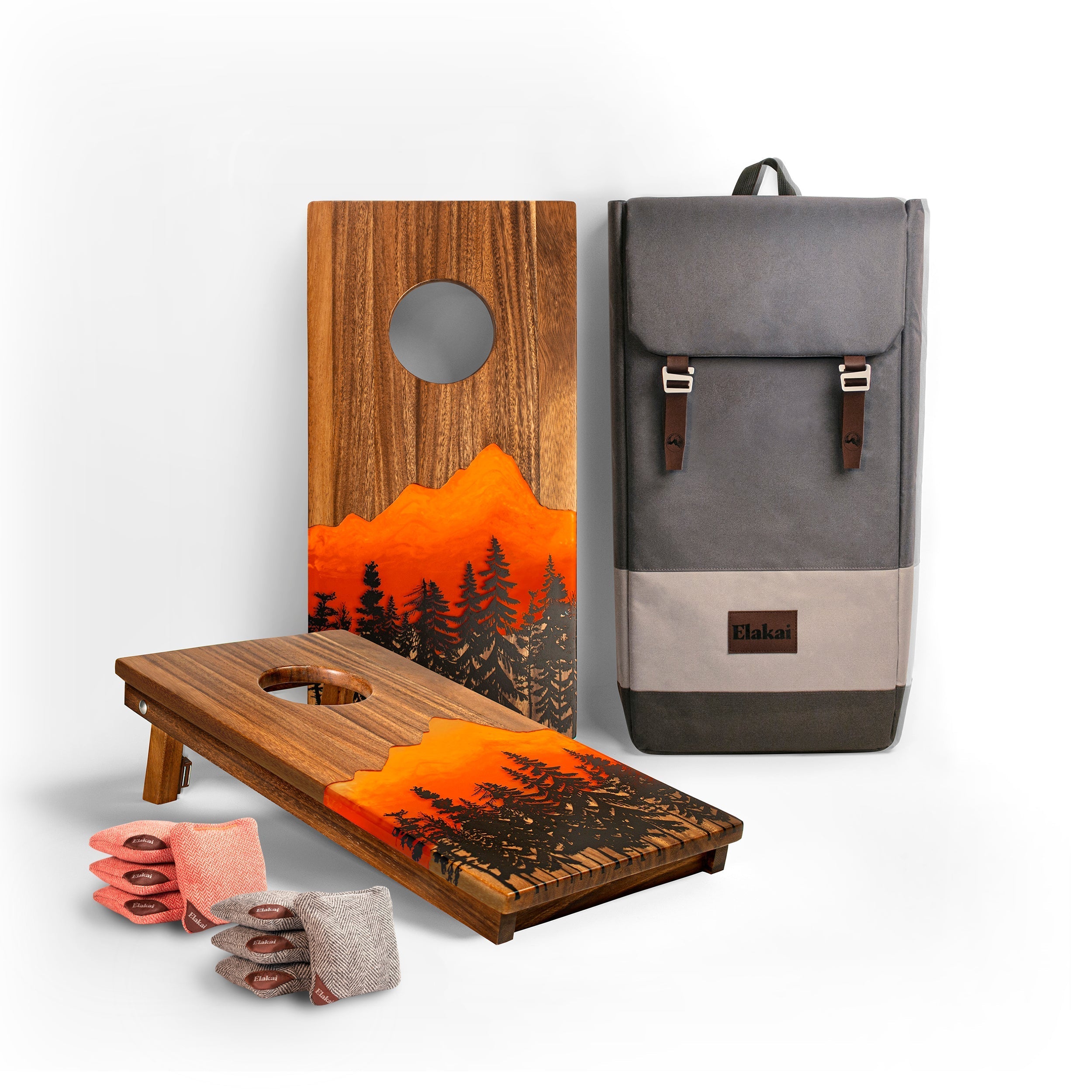 Two wooden cornhole boards with a sunset design and a gray backpack on a white background.