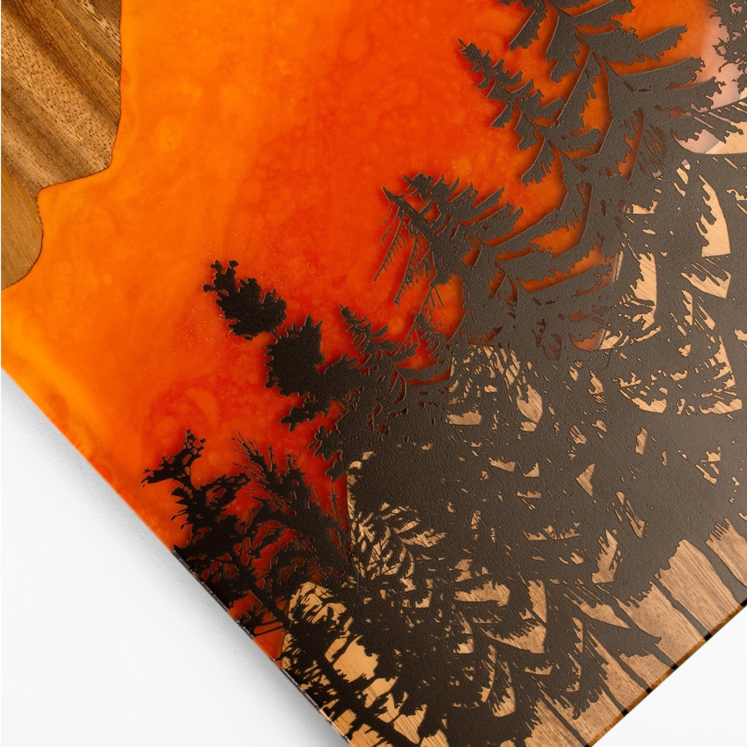 Wooden cutting board with laser-cut design of trees on an orange background