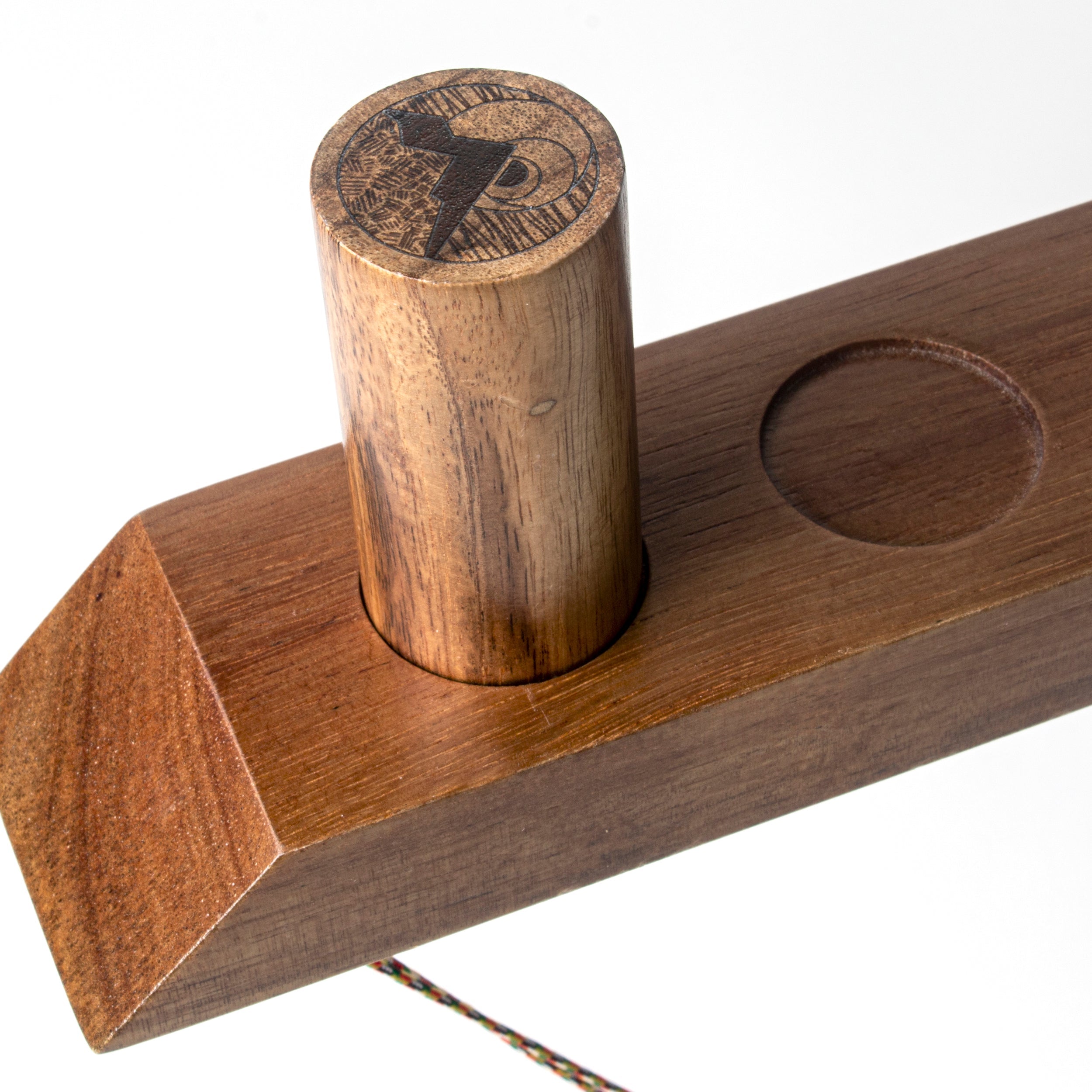 Wooden tool with cylindrical component and engraved design on a white background