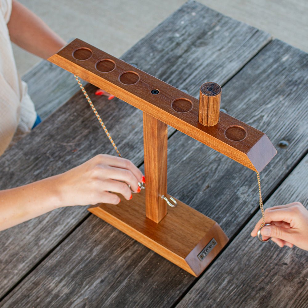 Wooden ring toss game on a wooden table with hands interacting with it