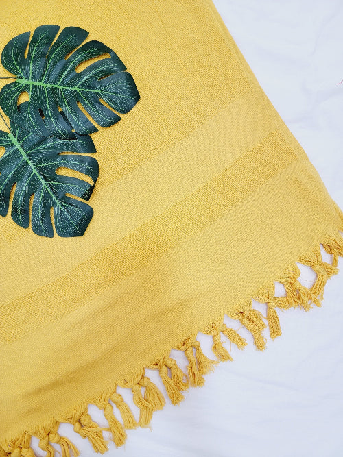 Yellow towel with green leaf design on a white background