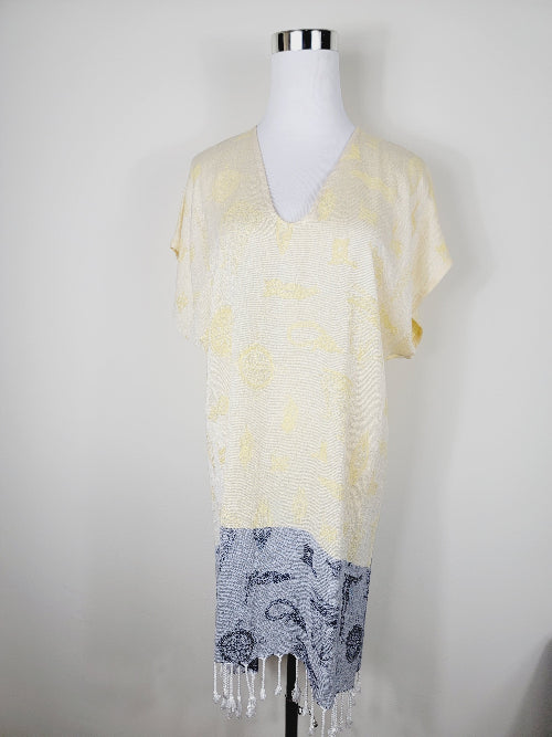 Mannequin wearing a yellow and gray patterned top with fringe on a white background