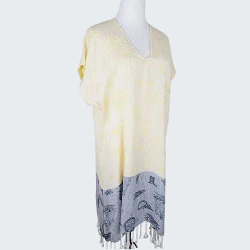 Mannequin wearing a light yellow scarf with gray fringe on a plain background