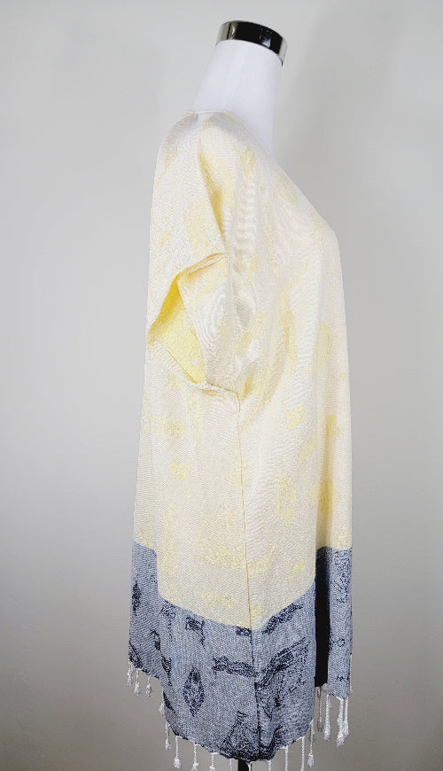 Mannequin wearing a yellow and gray patterned scarf with fringe on a plain background
