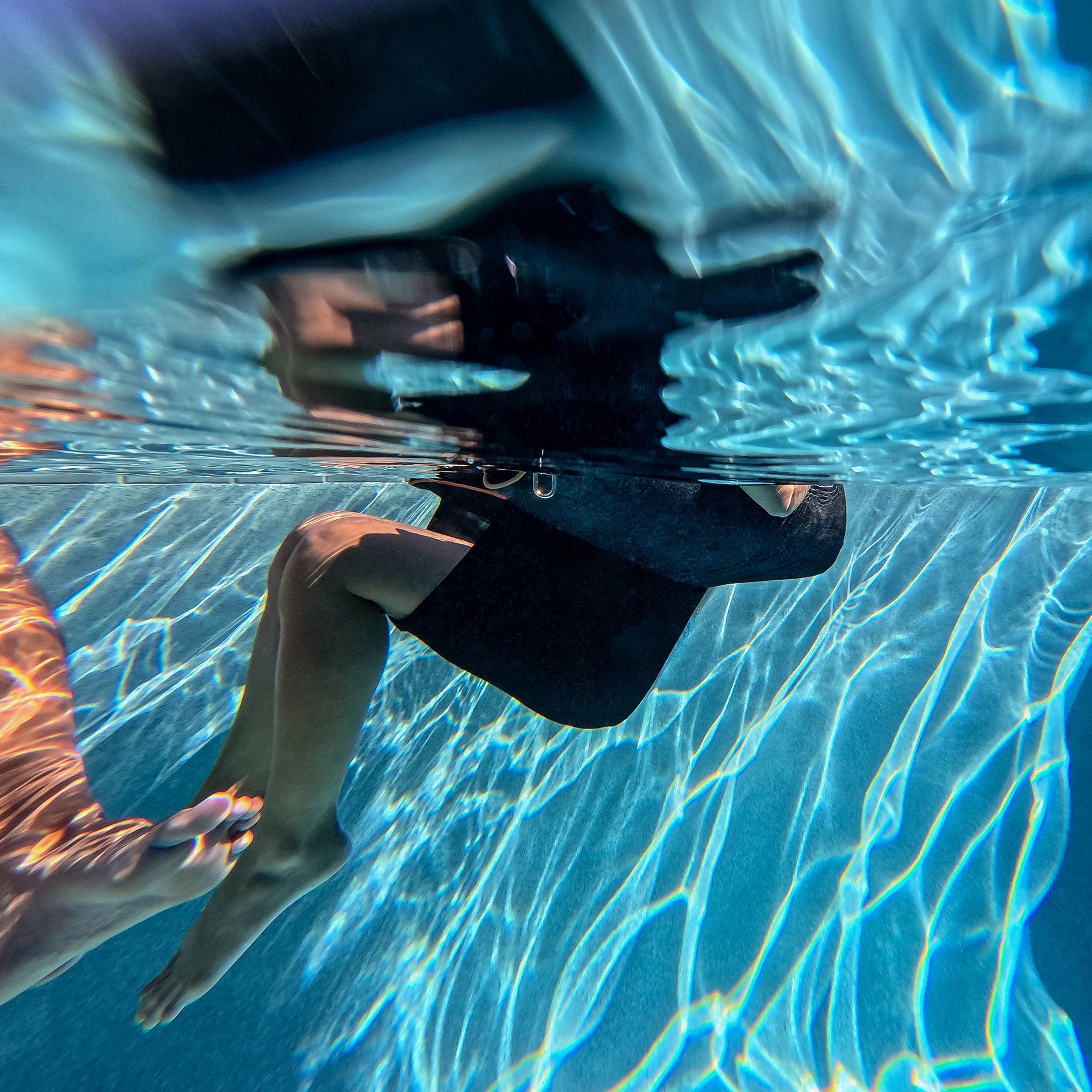 Person swimming underwater with a smartphone in a black case.