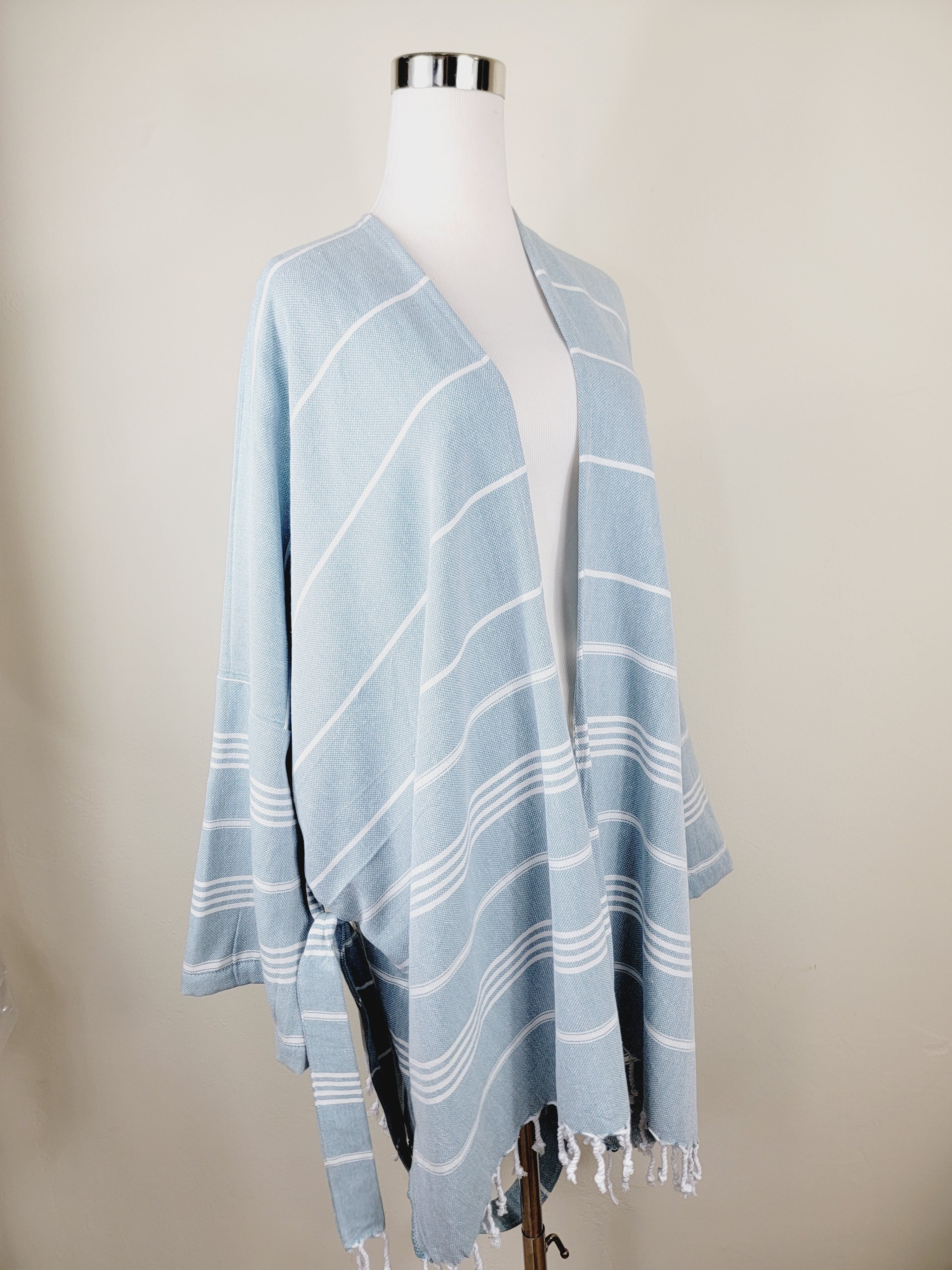 Light blue striped shawl on a mannequin against a beige background