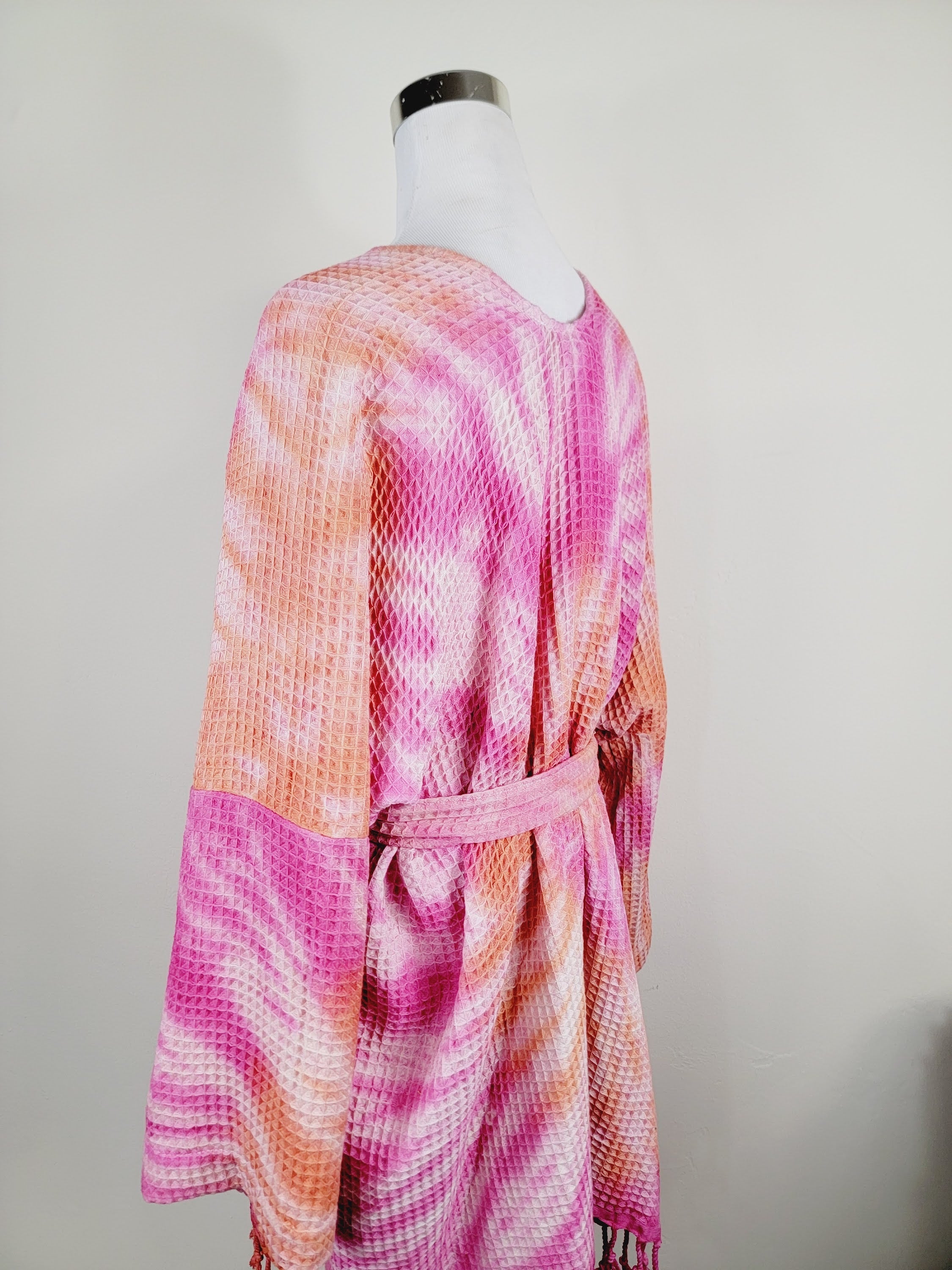Mannequin wearing a pink and orange tie-dye dress against a plain background