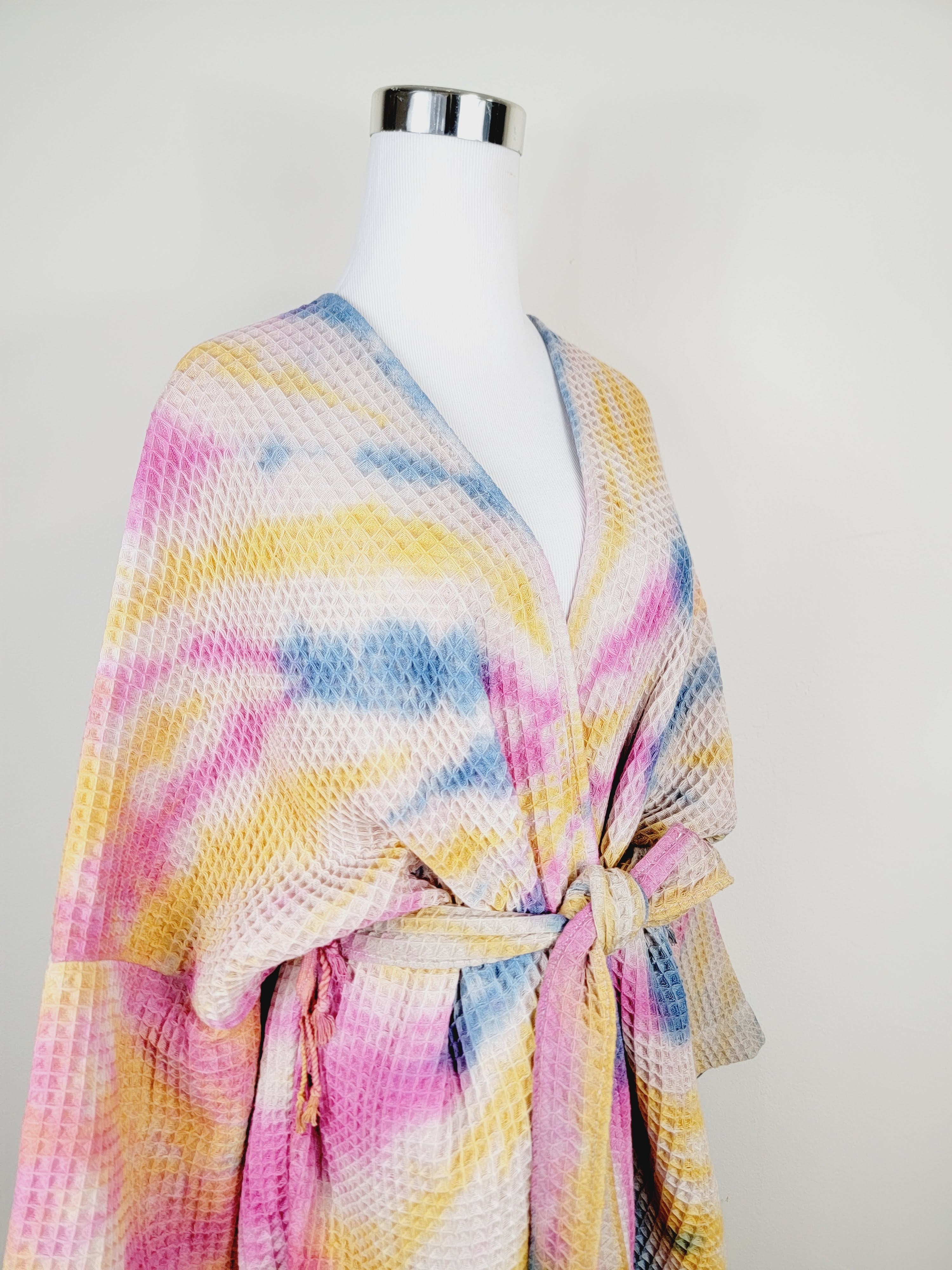Colorful tie-dye robe on a mannequin against a plain background
