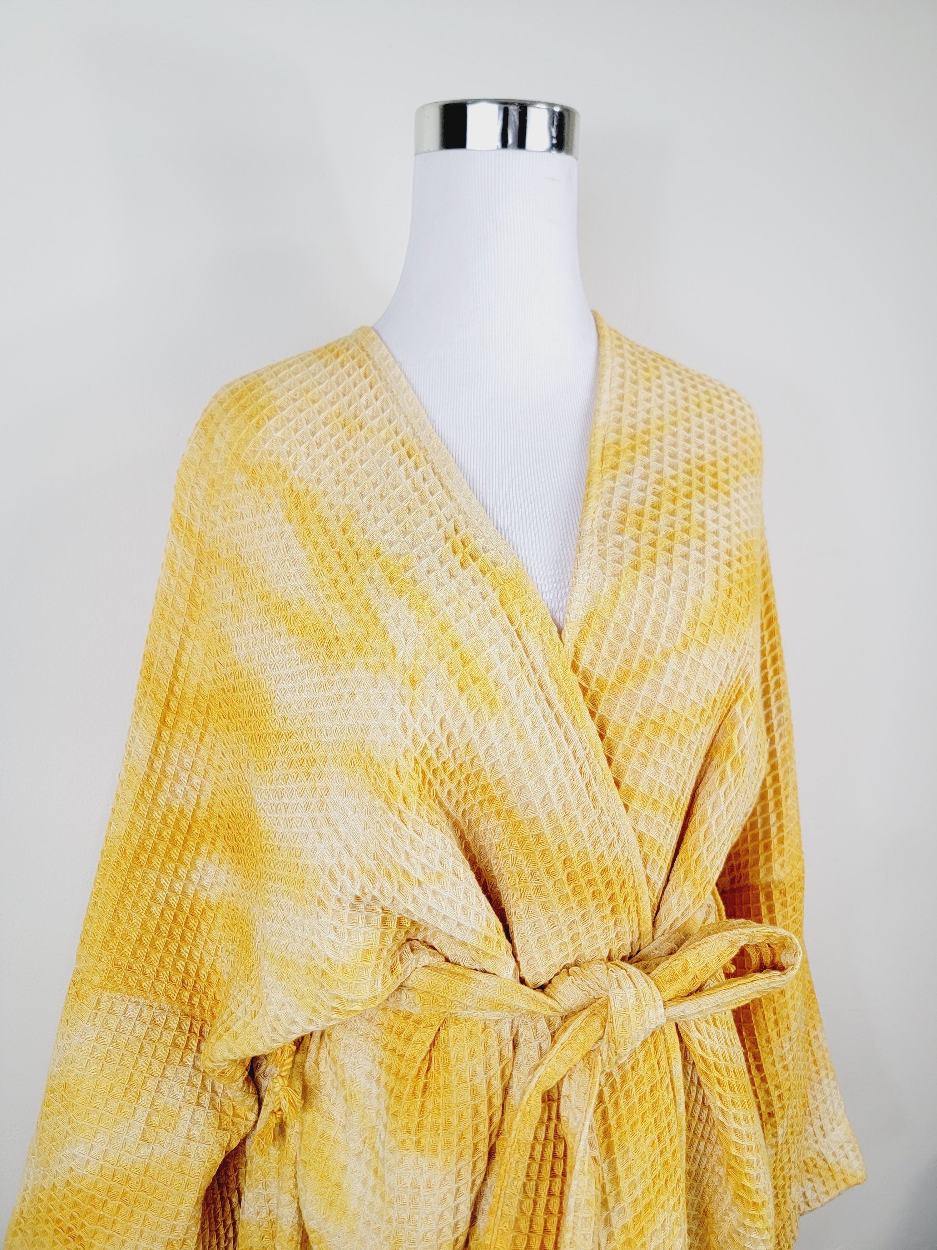 Yellow textured robe on a mannequin against a white background