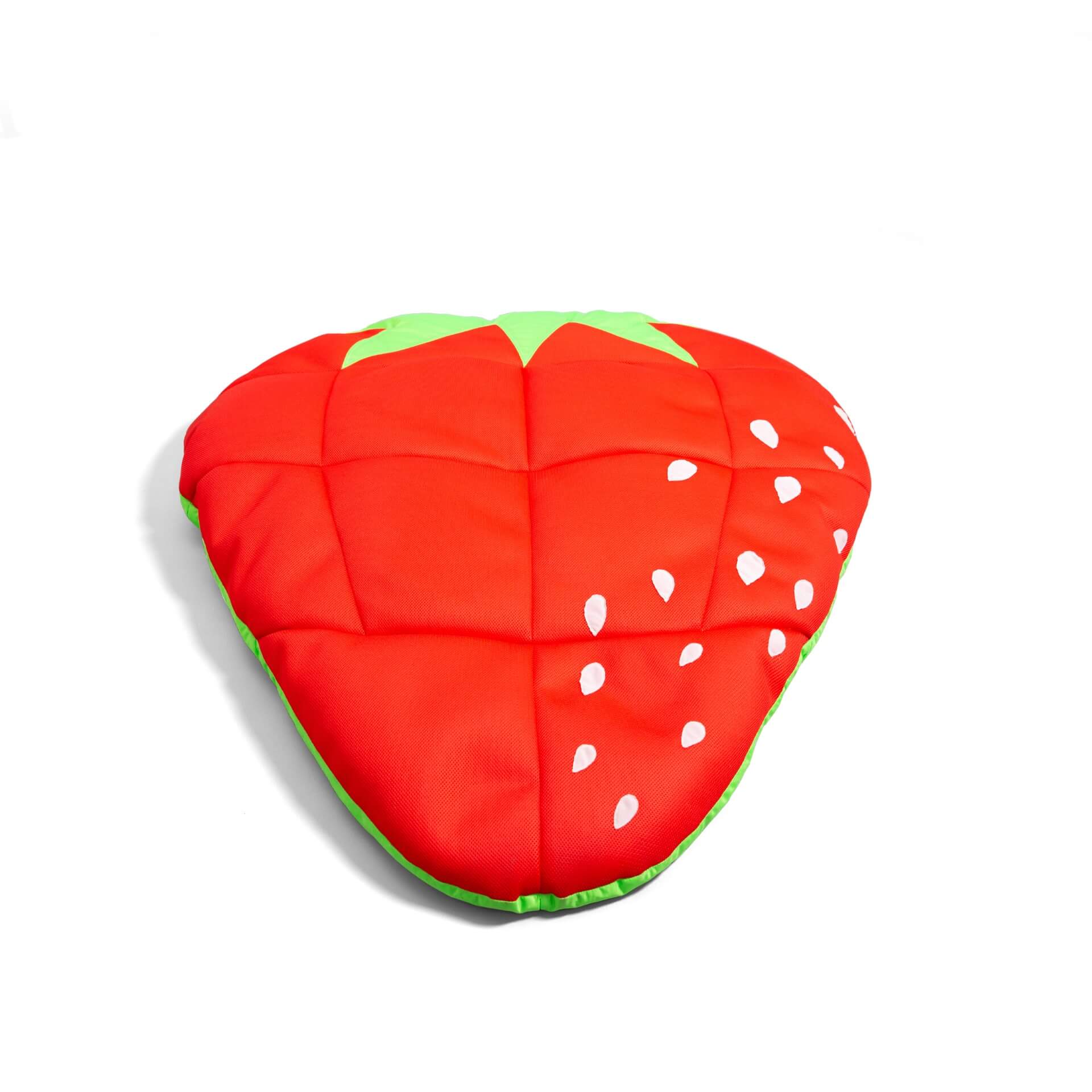 Strawberry-shaped cushion with red body, green leaves, and white seeds on a white background