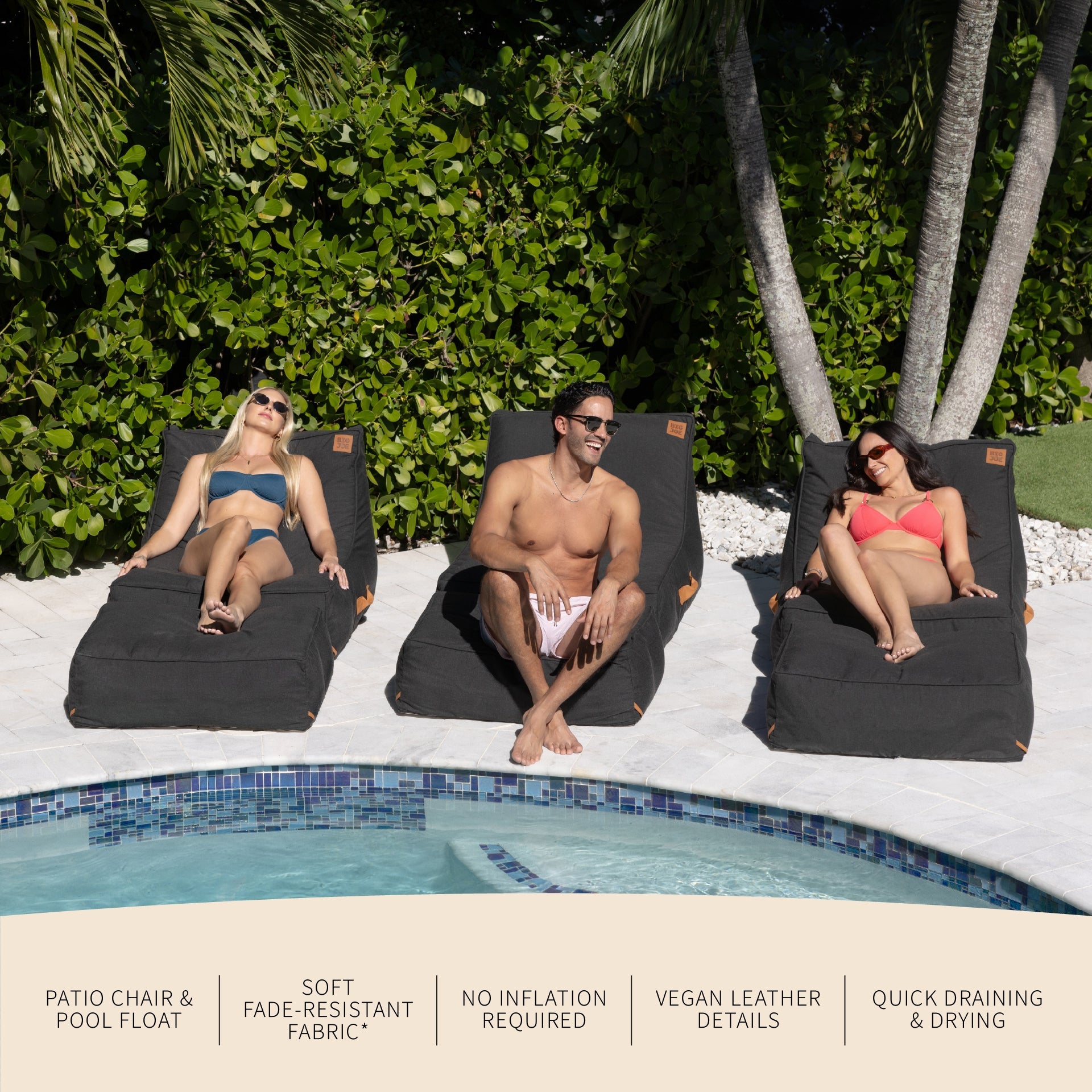 Three people relaxing on black pool chairs by a pool with greenery in the background.