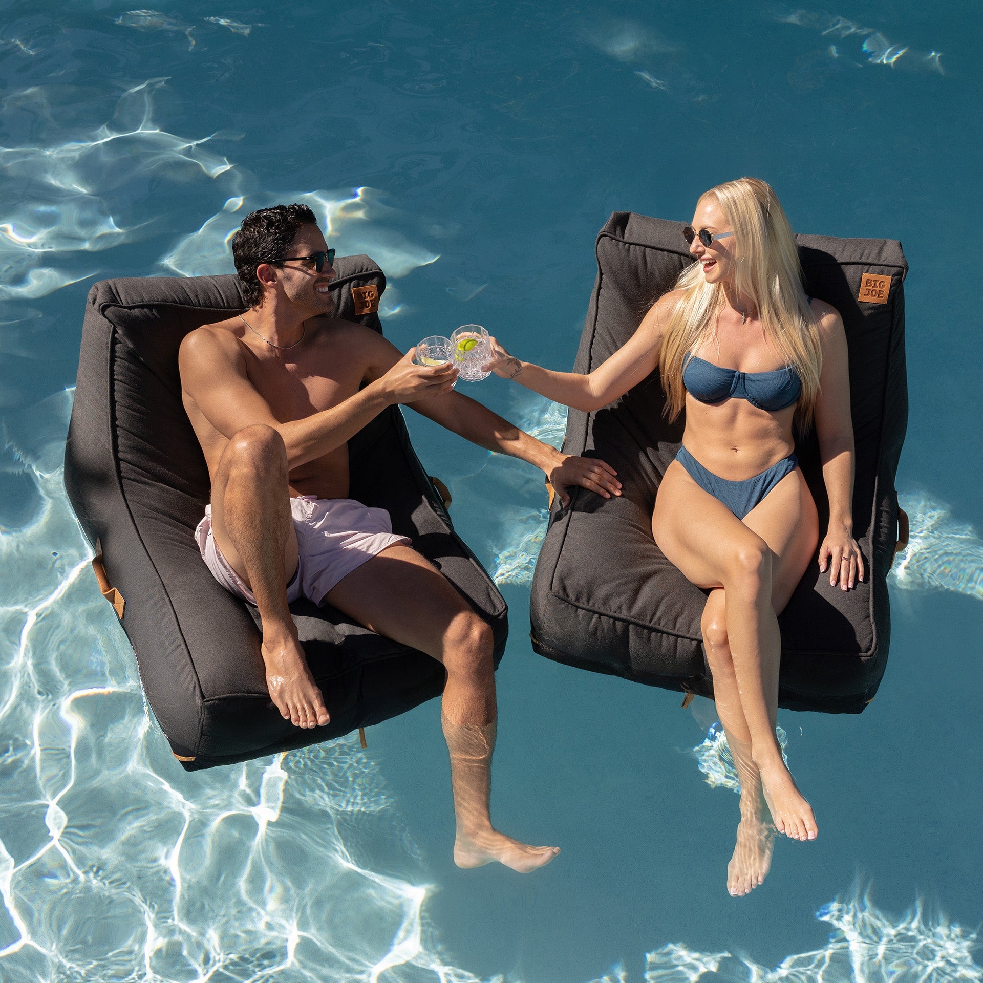Two people sitting in悬浮式躺椅 by a pool