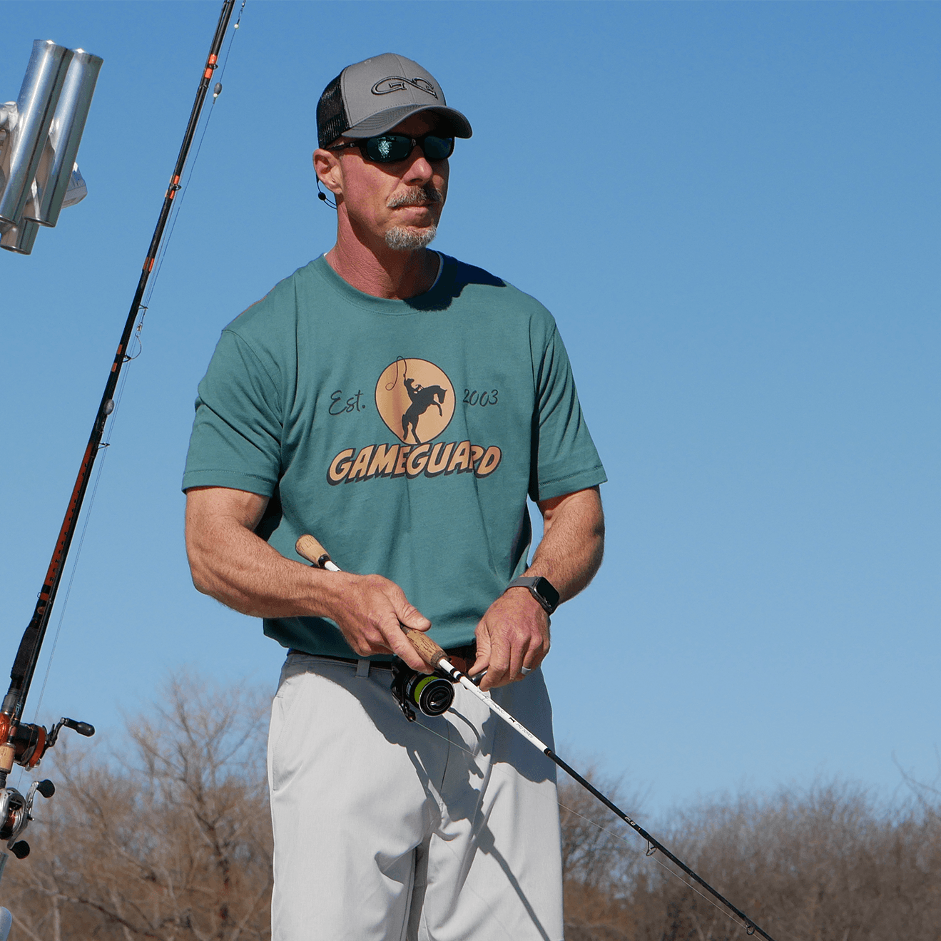 Man holding a fishing rod with a clear blue sky background