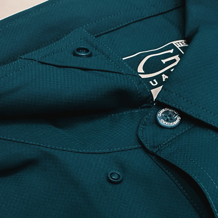 Close-up of a teal shirt with a brand tag and buttons.